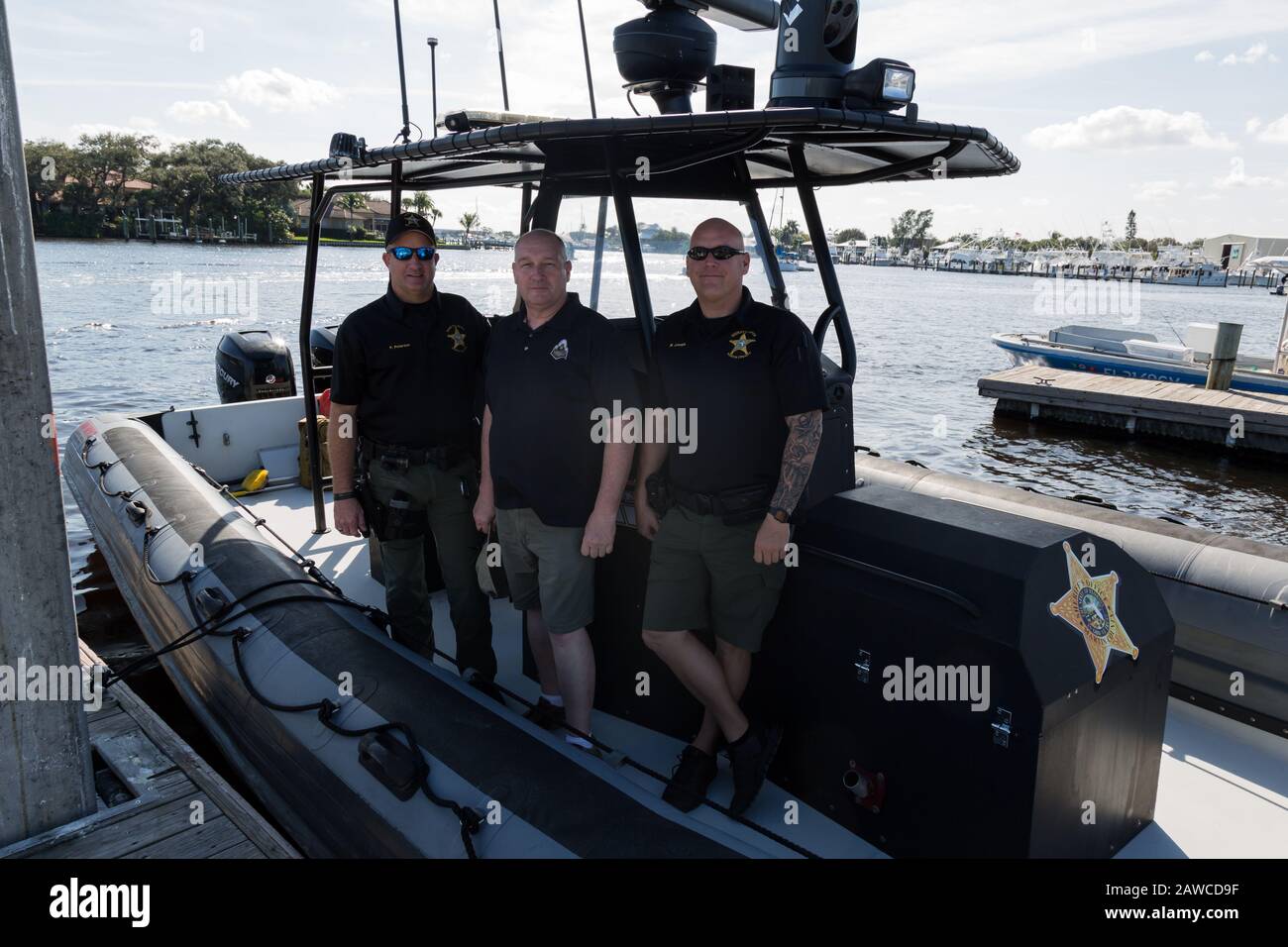 Deputies Michael Joseph and Pete Peterson pose with a tourist on the Manatee Pocket at Sandsprit Park in Port Salerno, Florida, USA. Stock Photo