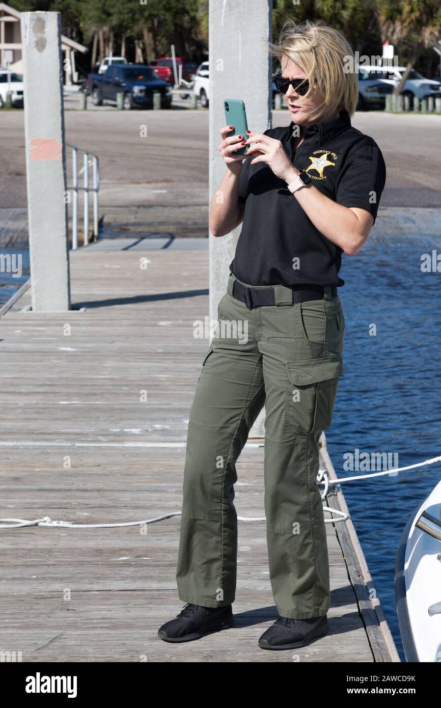 Trisha Kukuvka, Martin County Sheriff's Dept., takes a photo while on a pier at the Manatee Pocket in Sandsprit Park in Port Salerno, Florida, USA. Stock Photo