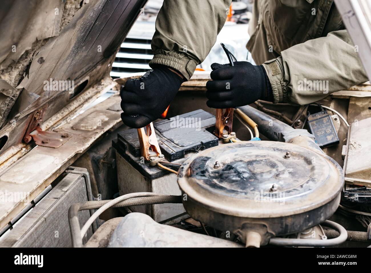Mechanic engineer charging car battery with electricity using jumper