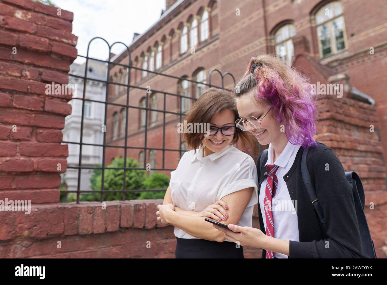 Female student walking and talking with woman teacher, girl showing on ...