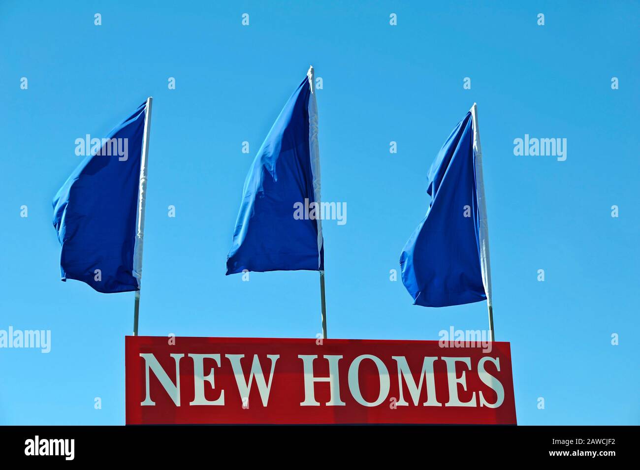 Red Real Estate Sign advertising New Homes with Blue Flags Stock Photo