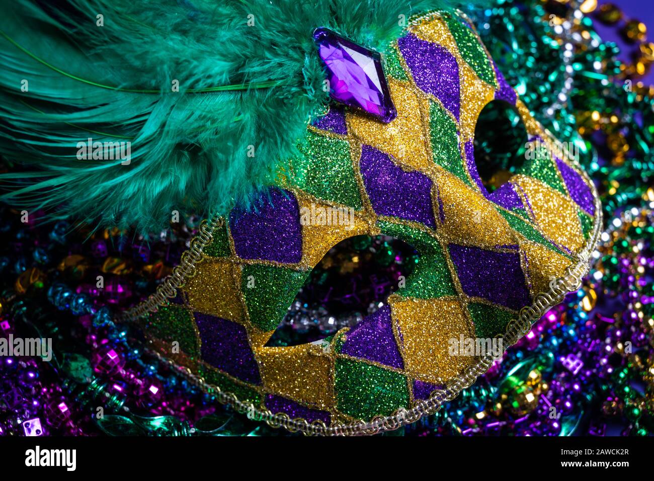 Colorful Mardi Gras mask on purple background with beads Stock Photo