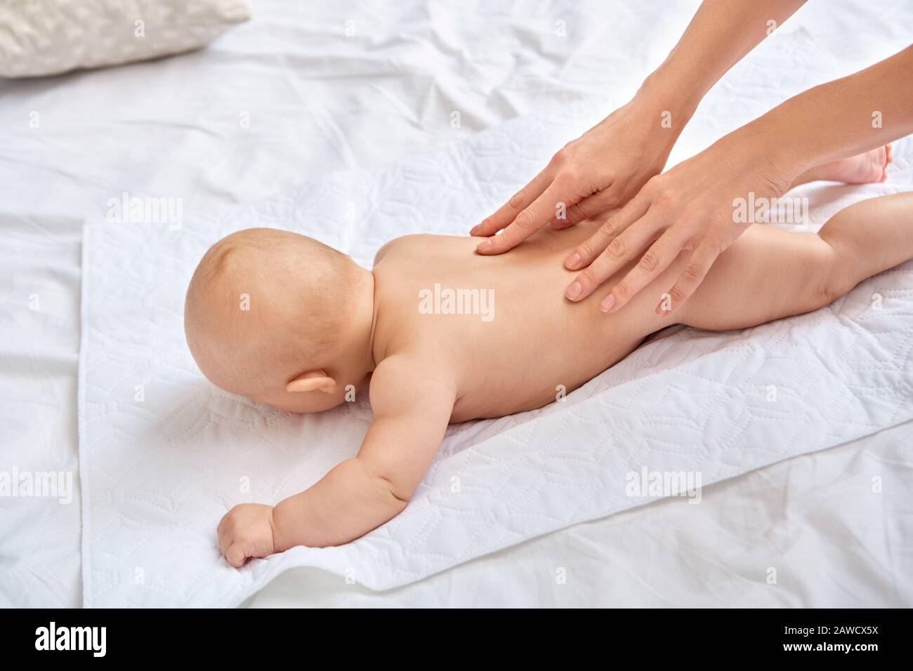 Baby Care. Young mother doing pediatric massage massaging back to little  son lying on bed close-up Stock Photo - Alamy