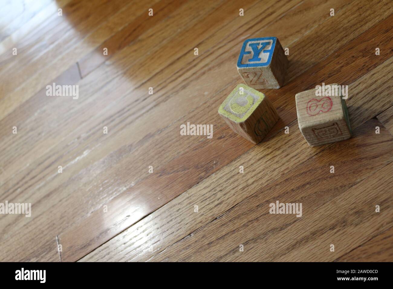 Three Old Wooden Colorful Alphabet Number Blocks on wood floor in natural light Stock Photo