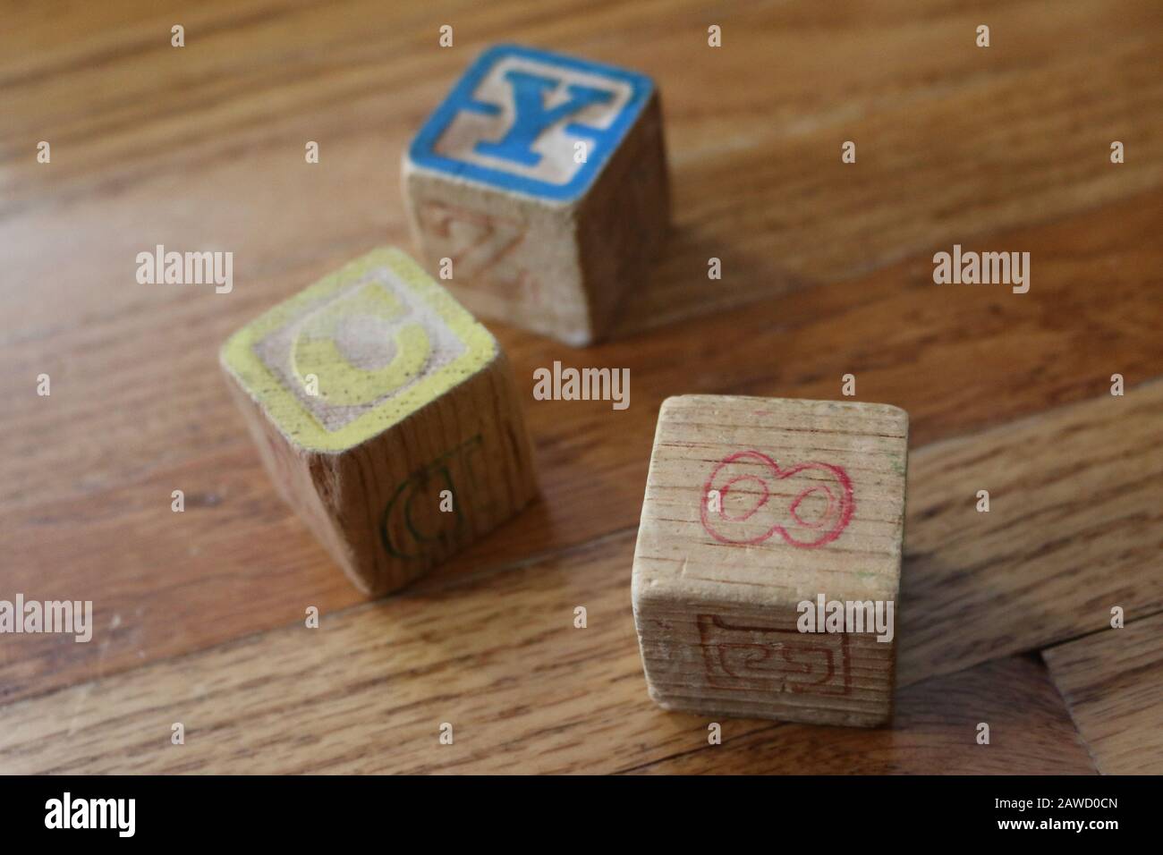 Three Old Wooden Colorful Alphabet Number Blocks on wood floor in natural light Stock Photo