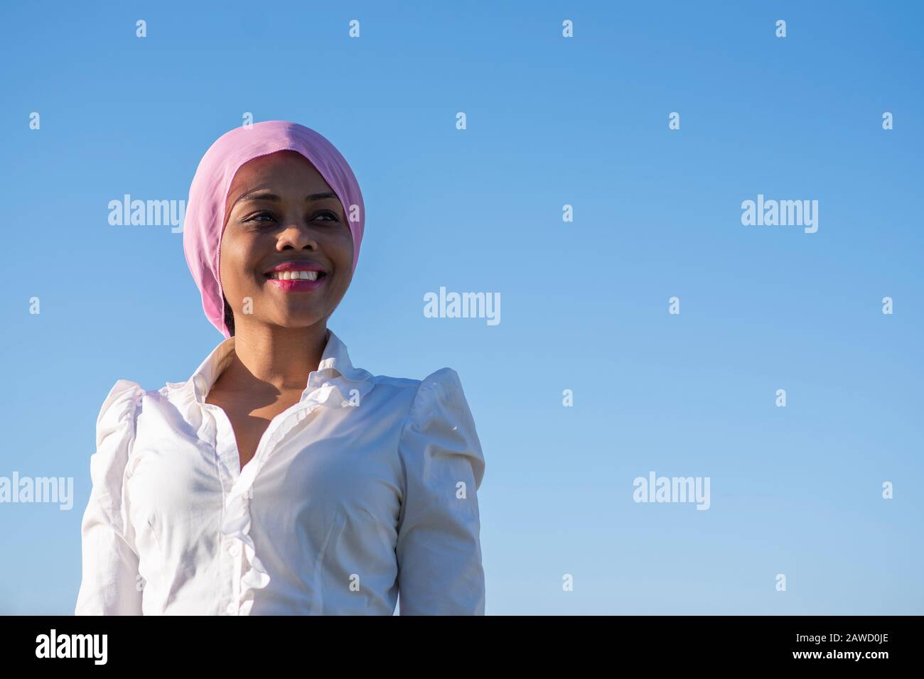 dark-skinned woman with a pink headscarf smiling Stock Photo