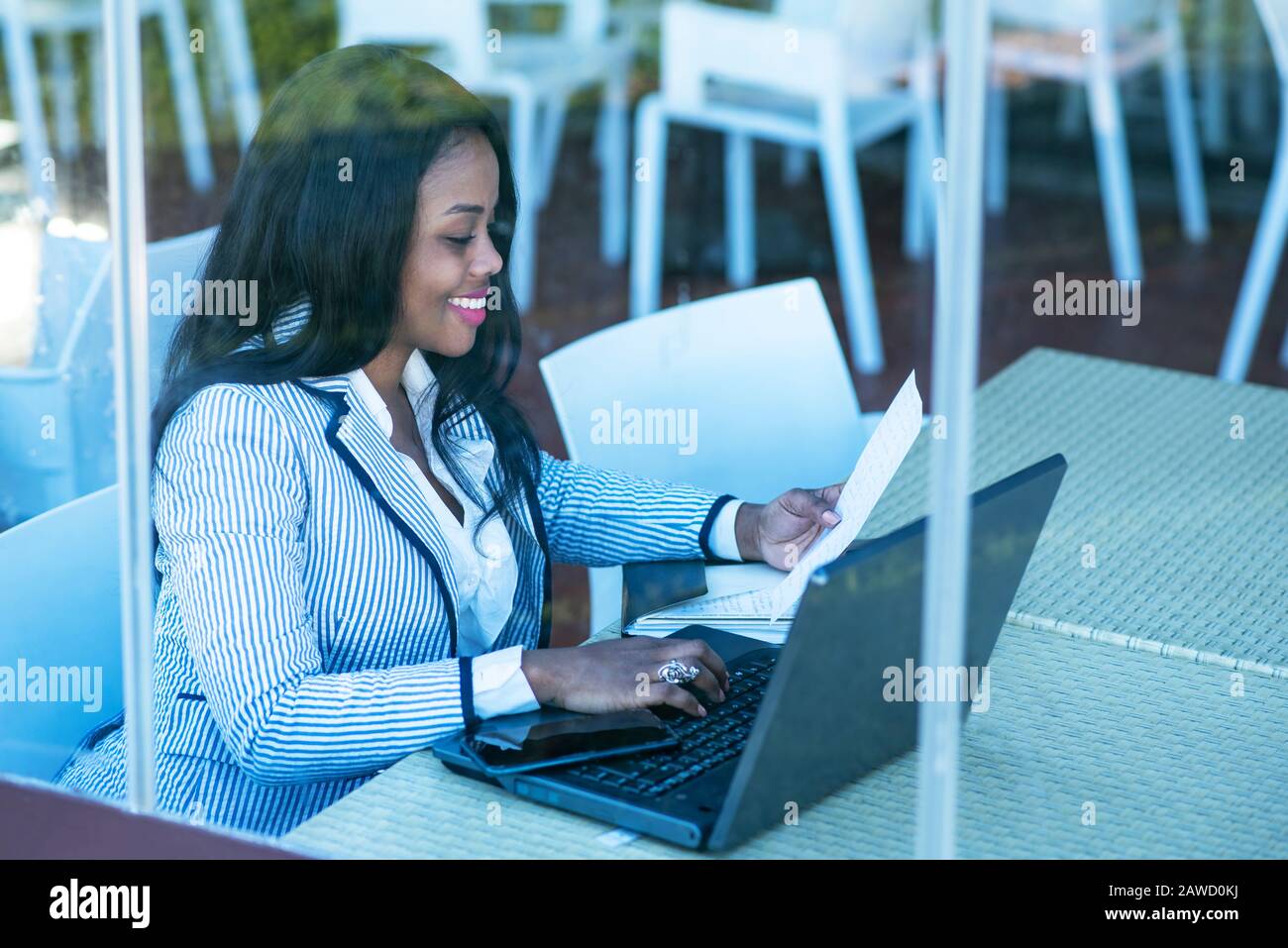 Beautiful African-American woman using a laptop and reading a document Stock Photo