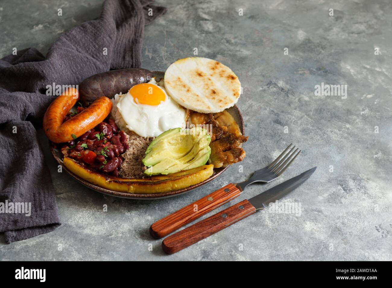 Colombian food. Bandeja paisa, typical dish at the Antioquia region of Colombia - chicharron (fried pork belly), black pudding, sausage, arepa, beans, Stock Photo