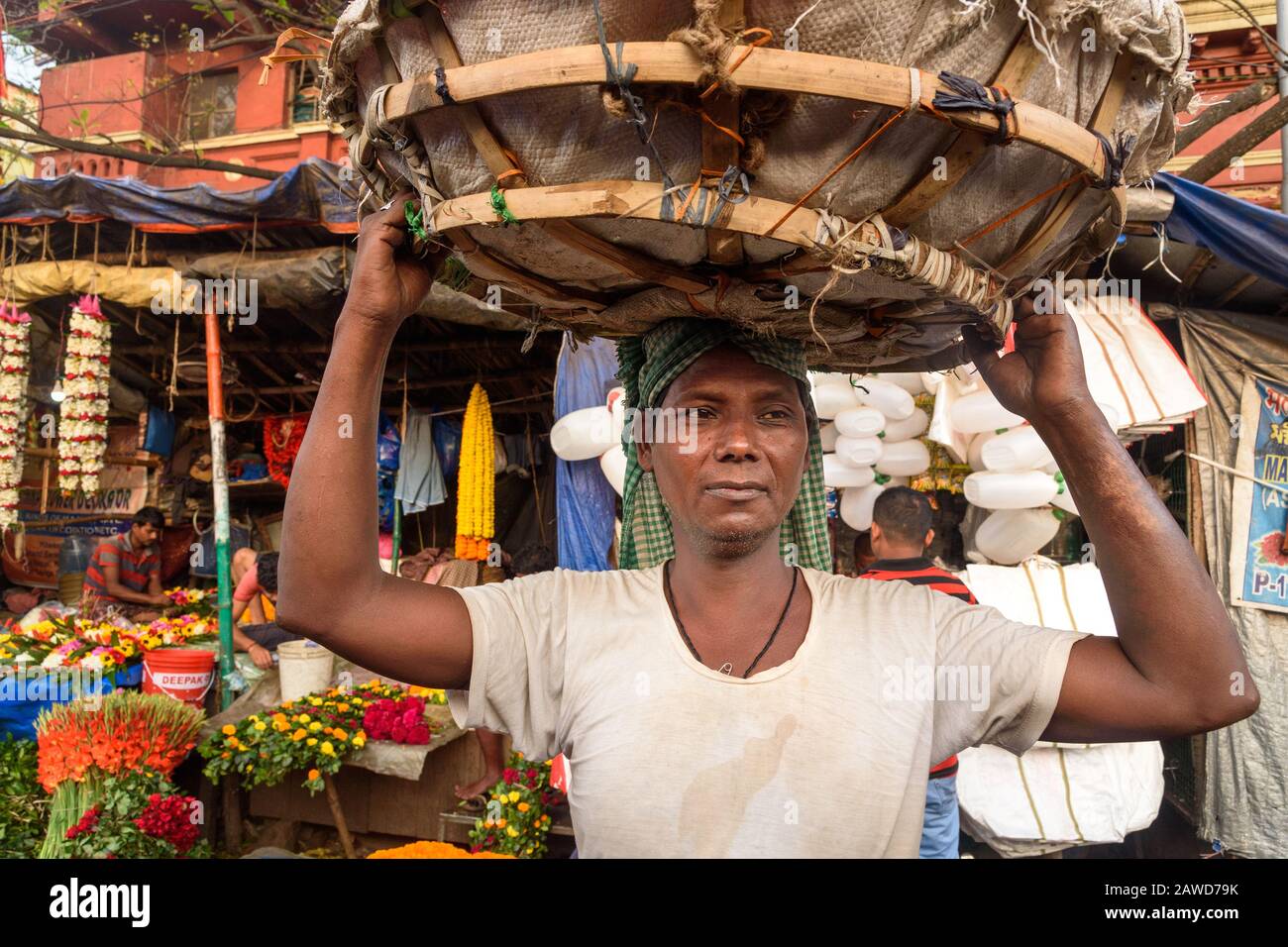 Indian man carrying flower basket on head in Flower market at Mallick