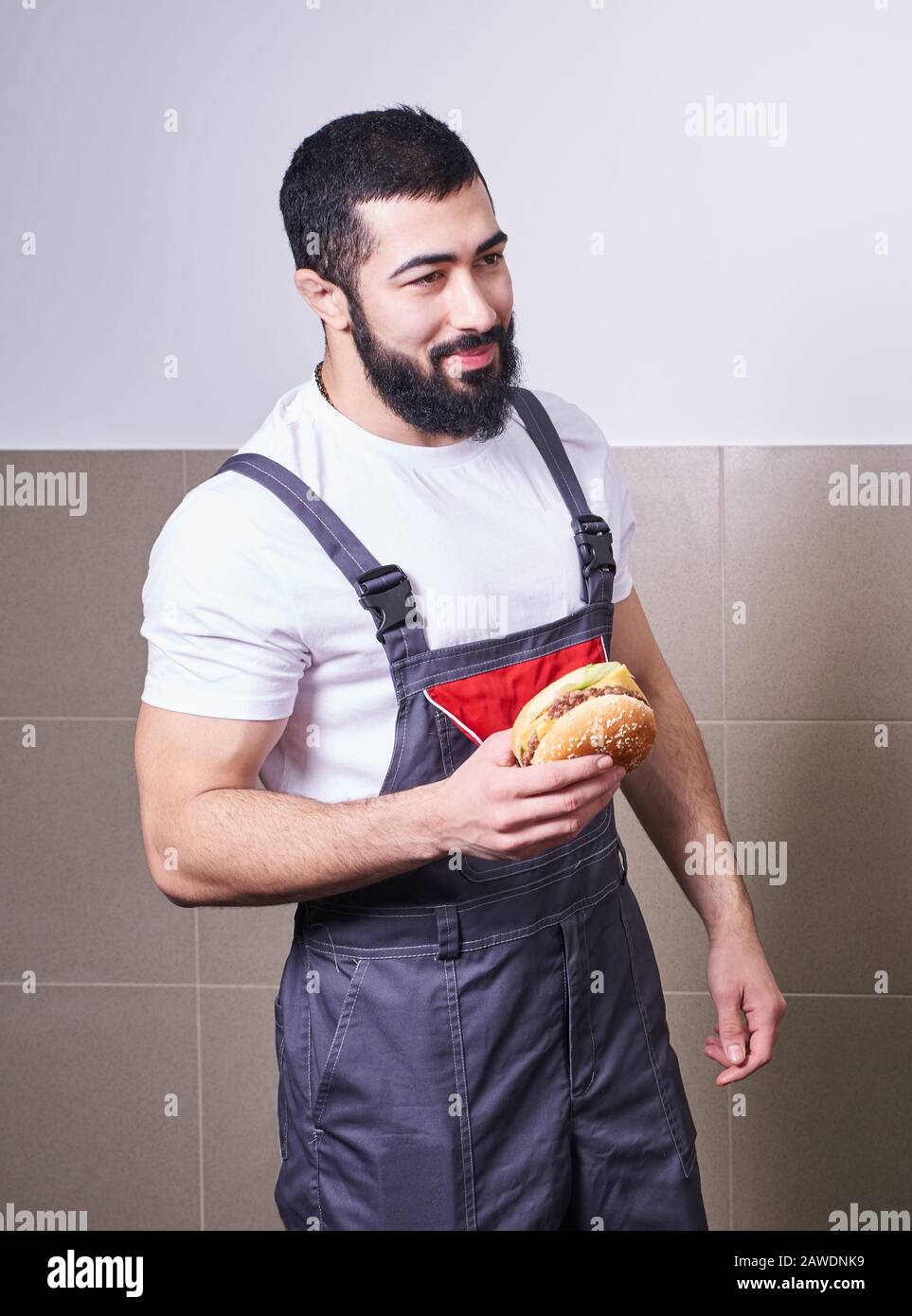 Worker wearing uniform eating burger during a lunch break Stock Photo