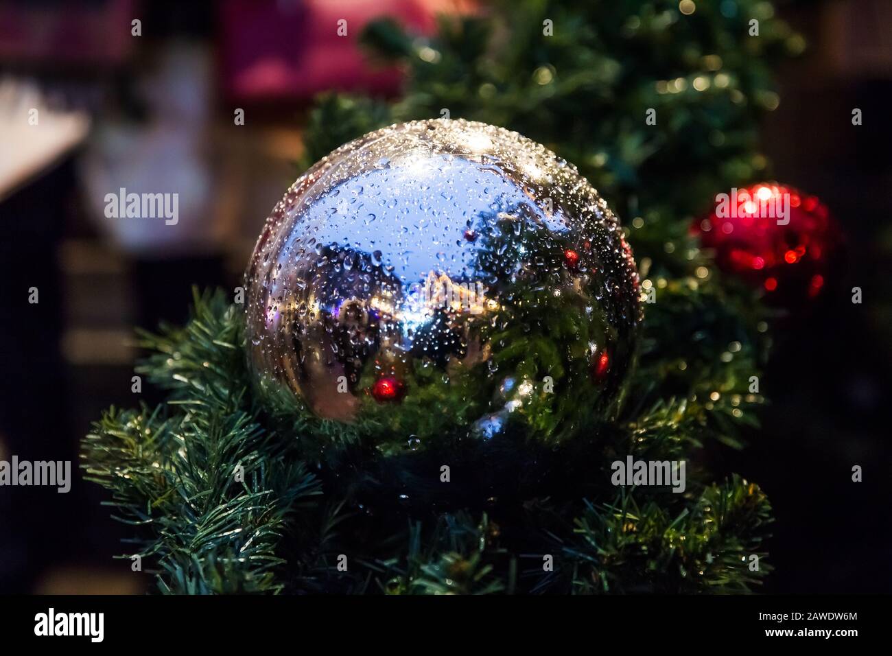 Closeup of red bauble hanging from a decorated Christmas tree. Stock Photo