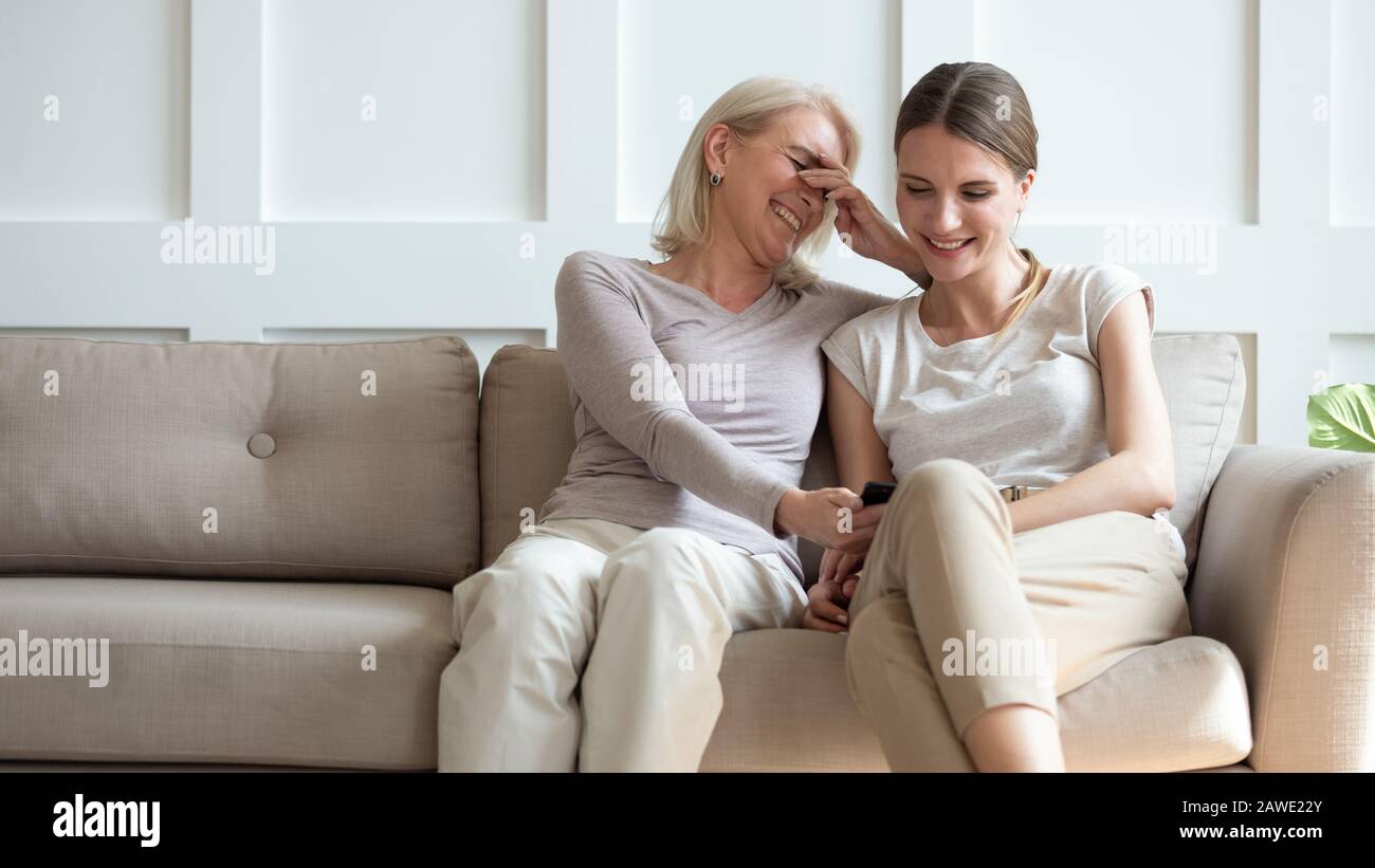 Smiling senior mom and daughter watch funny video on cell Stock Photo -  Alamy