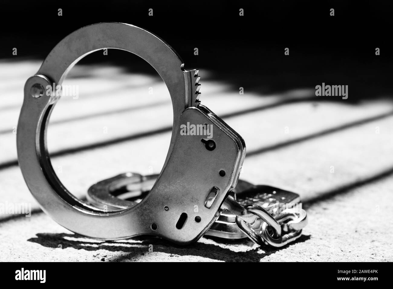 Handcuff with Jail Bars in Shadows Stock Photo