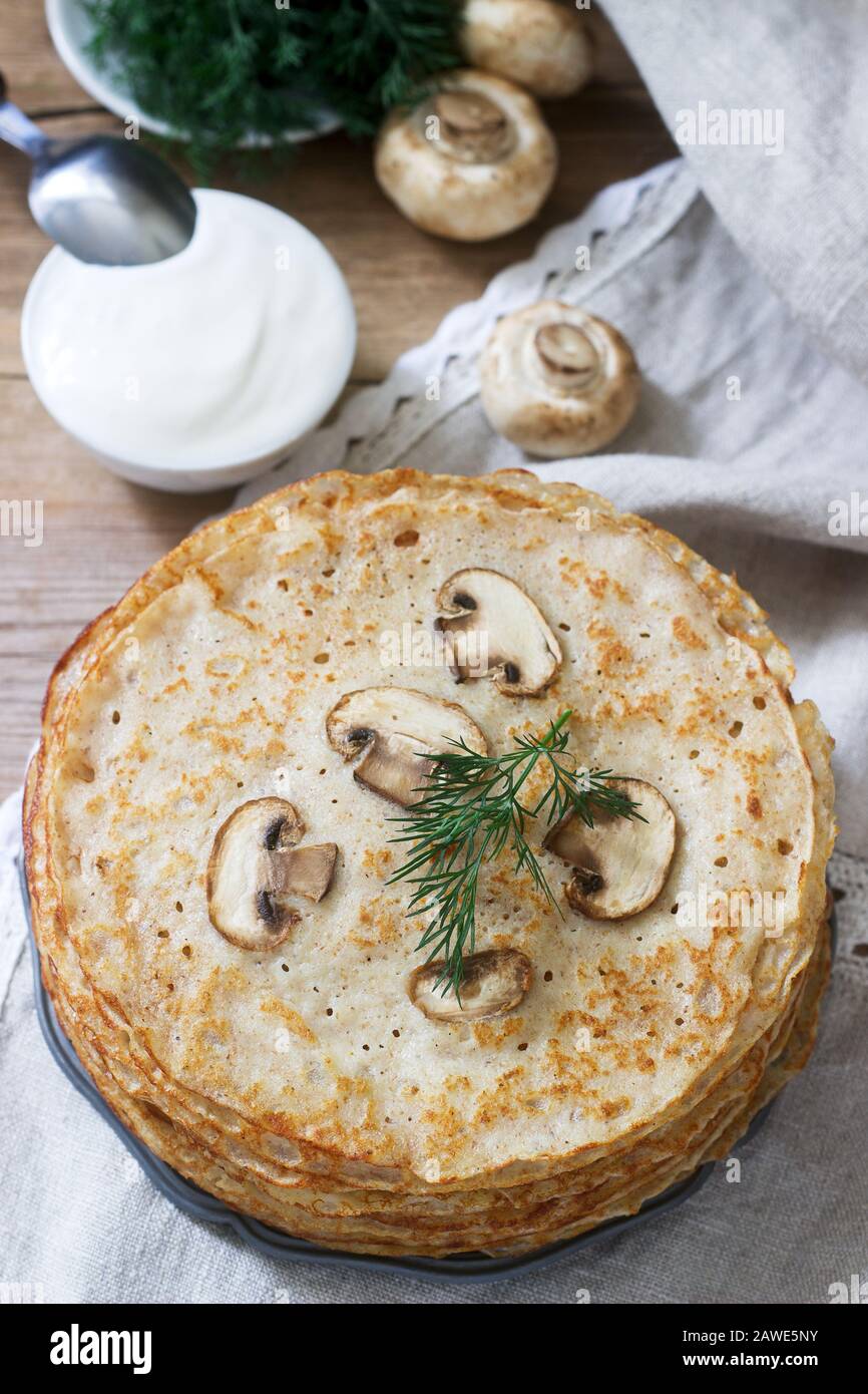 Buckwheat pancakes served with sour cream and dill on a wooden table. Rustic style. Stock Photo