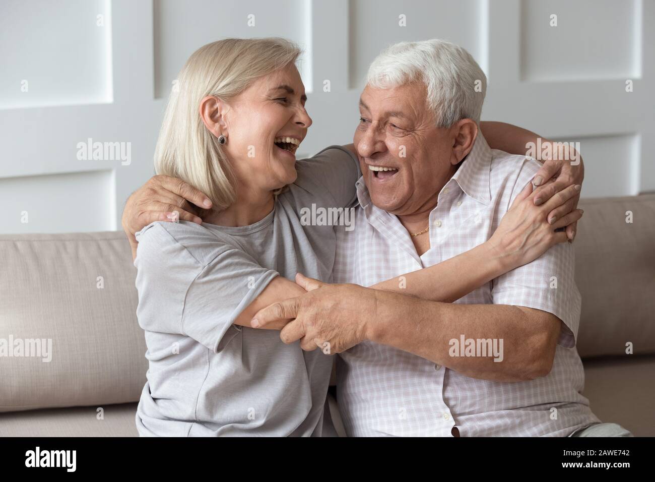 Funny elderly couple have fun laughing cuddling at home Stock Photo