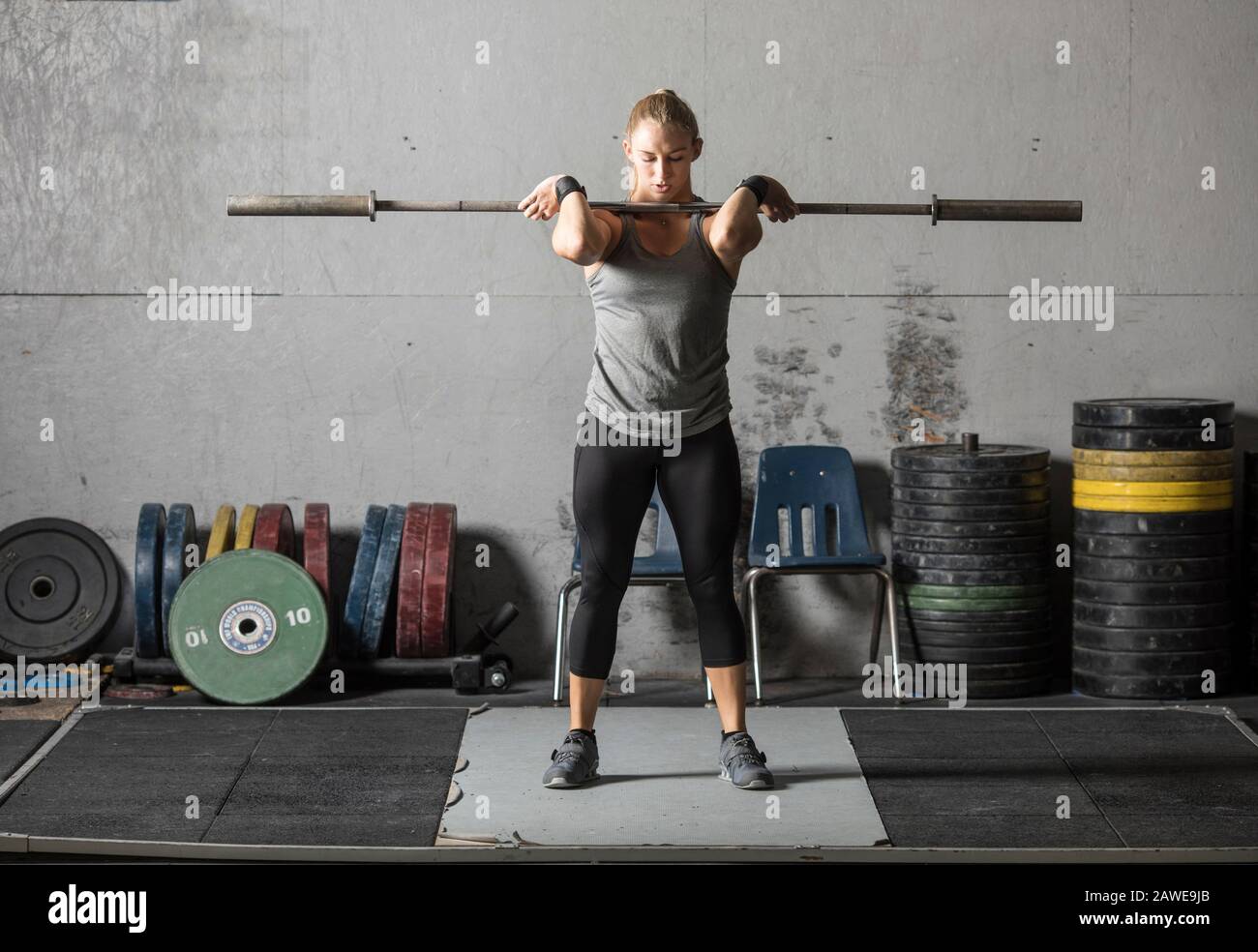 Young woman warming up and getting ready for heavy lifting in gym. Stock Photo