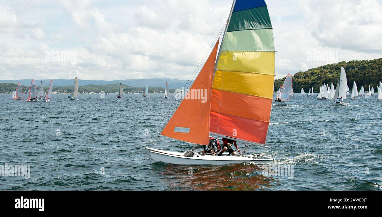 Children sailing in small colourful boats and dinghies for fun and in competition. Teamwork by junior sailors racing a catamaran on the saltwater lake Stock Photo