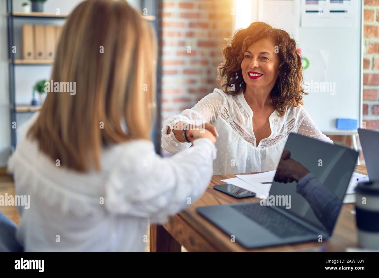 Two middle age beautiful businesswomen smiling happy and confident ...