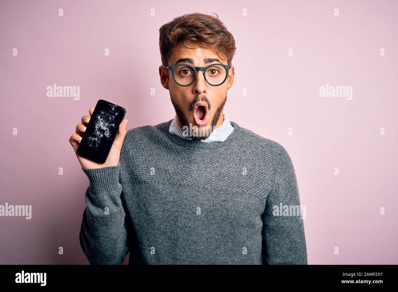 Young man with beard wearing glasses holding broken and craked ...
