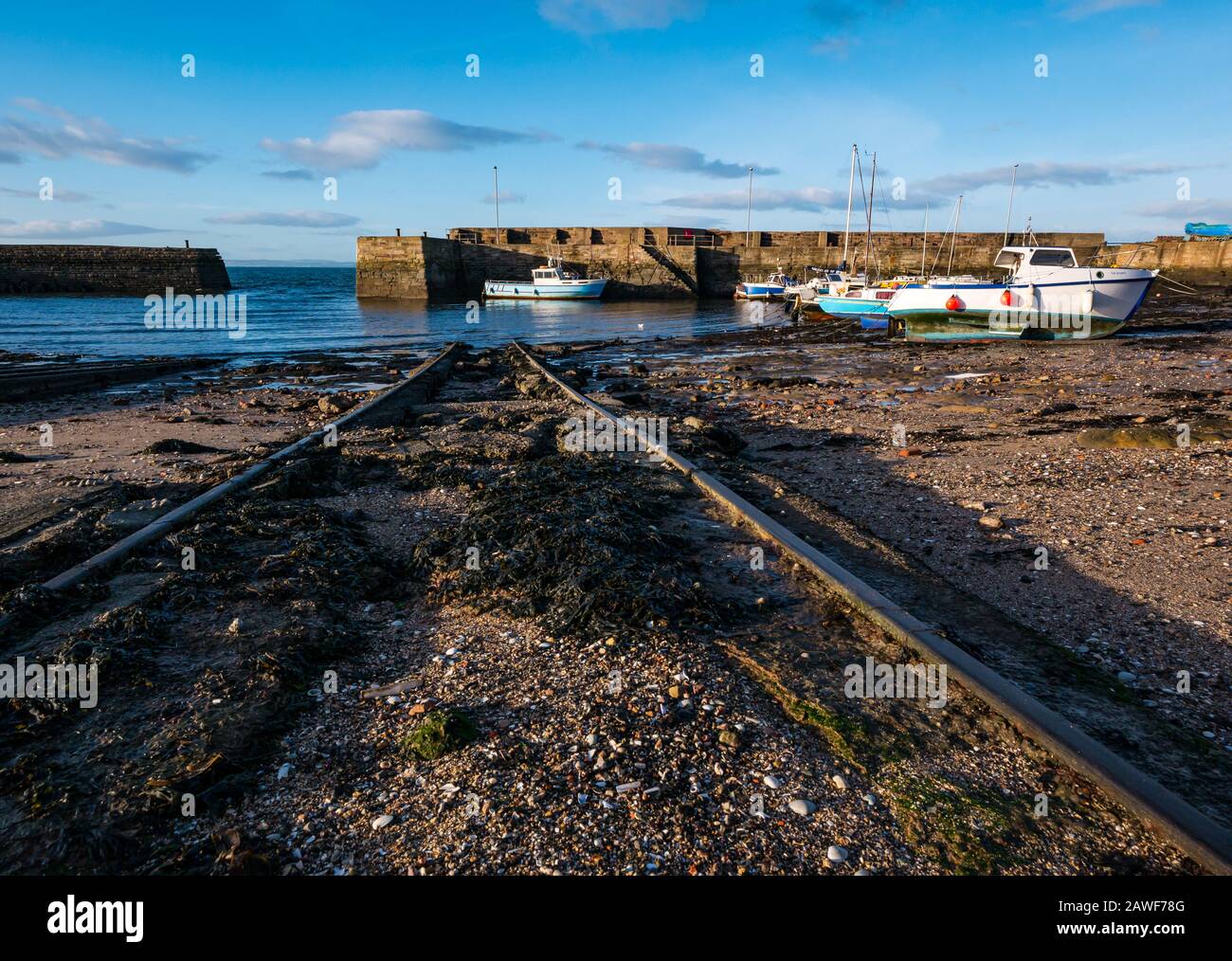 Small boats aground with slipway at low tide in sunshine, Cockenzie Harbour, East Lothian, Scotland, UK Stock Photo