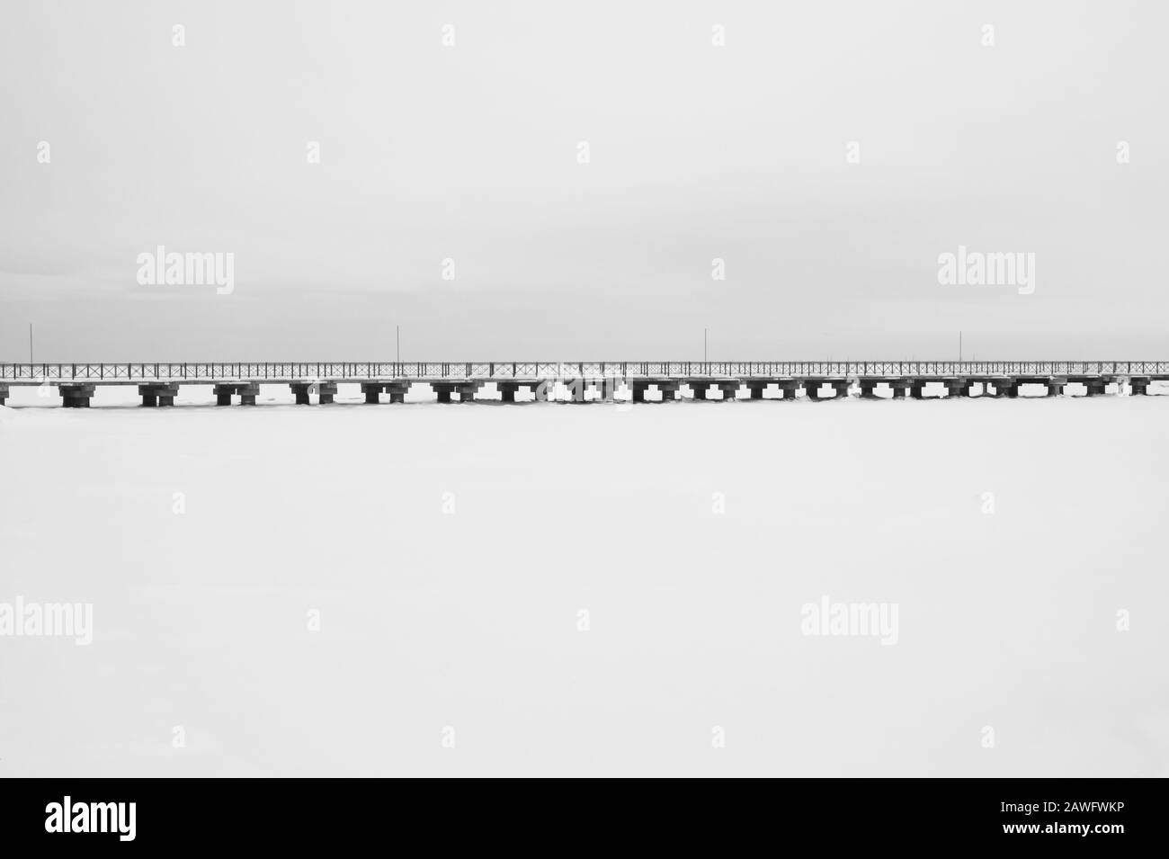 Bridge on the frozen lake. long footbridge dividing the horizon. conceptual minimalistic image. black and white background with copy space Stock Photo