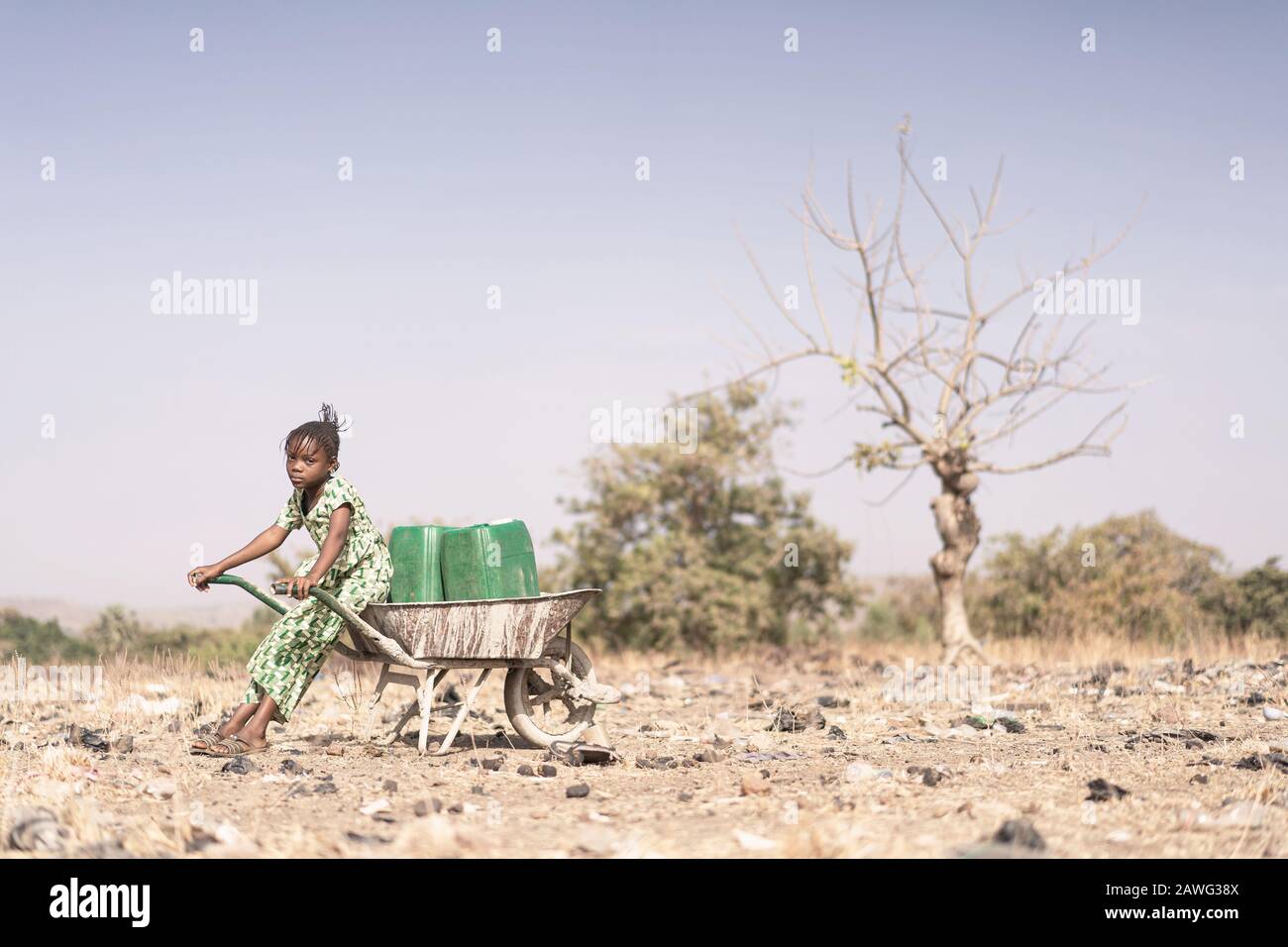 Tiny Native African Girl Carrying Fresh Water for an aridity concept Stock Photo