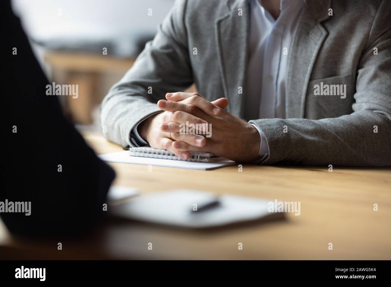 Two businessmen with clasped hands sitting opposite close up Stock Photo