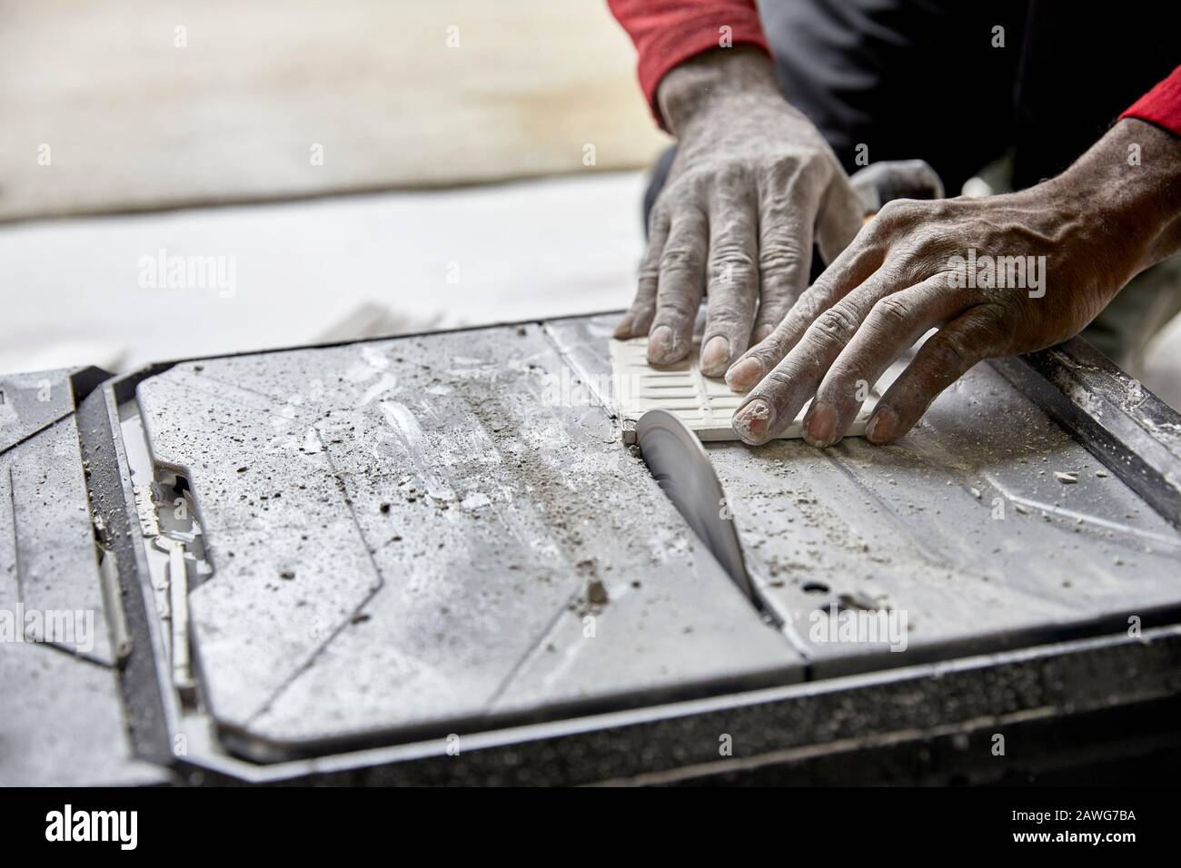 Close up of a man's hands using a tile saw to cut ceramic tile Stock