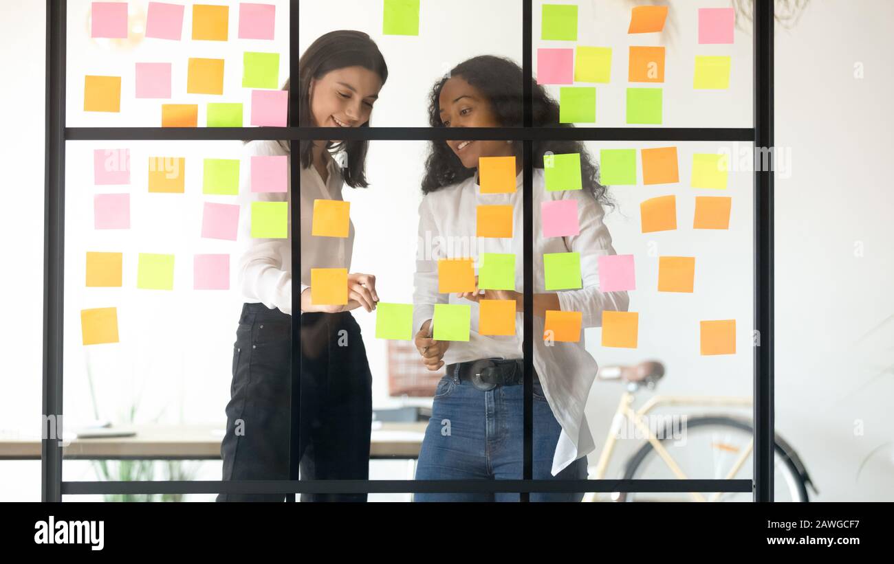 Two multiethnic affiliates create ideas writing it on sticky notes Stock Photo
