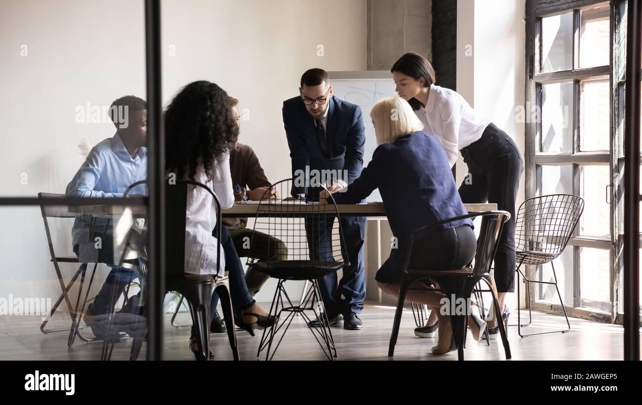 Multiethnic staff gathered at boardroom analyzing data brainstorming share thoughts Stock Photo
