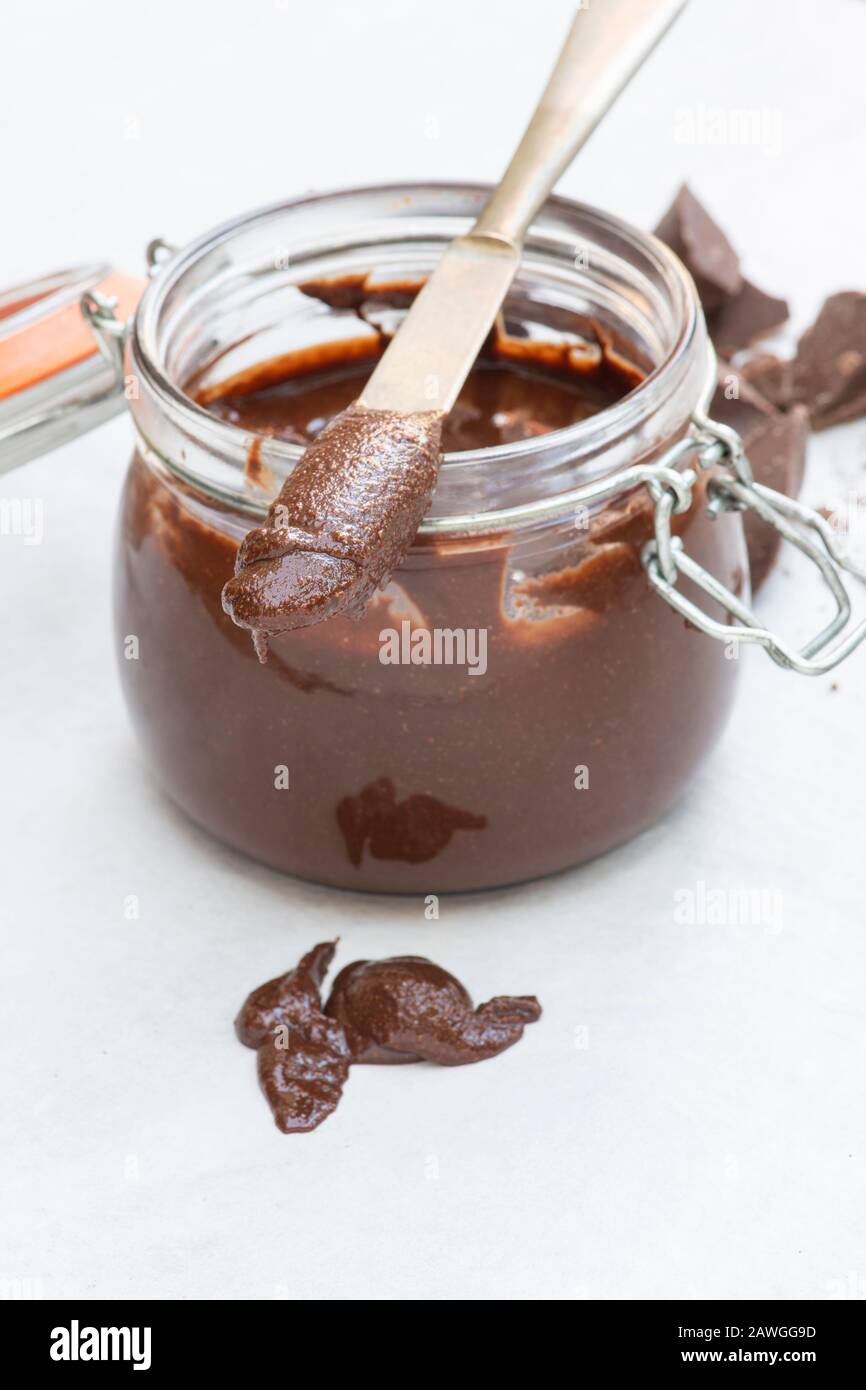 Homemade vegan hazelnut chocolate spread on a knife and in a kilner jar