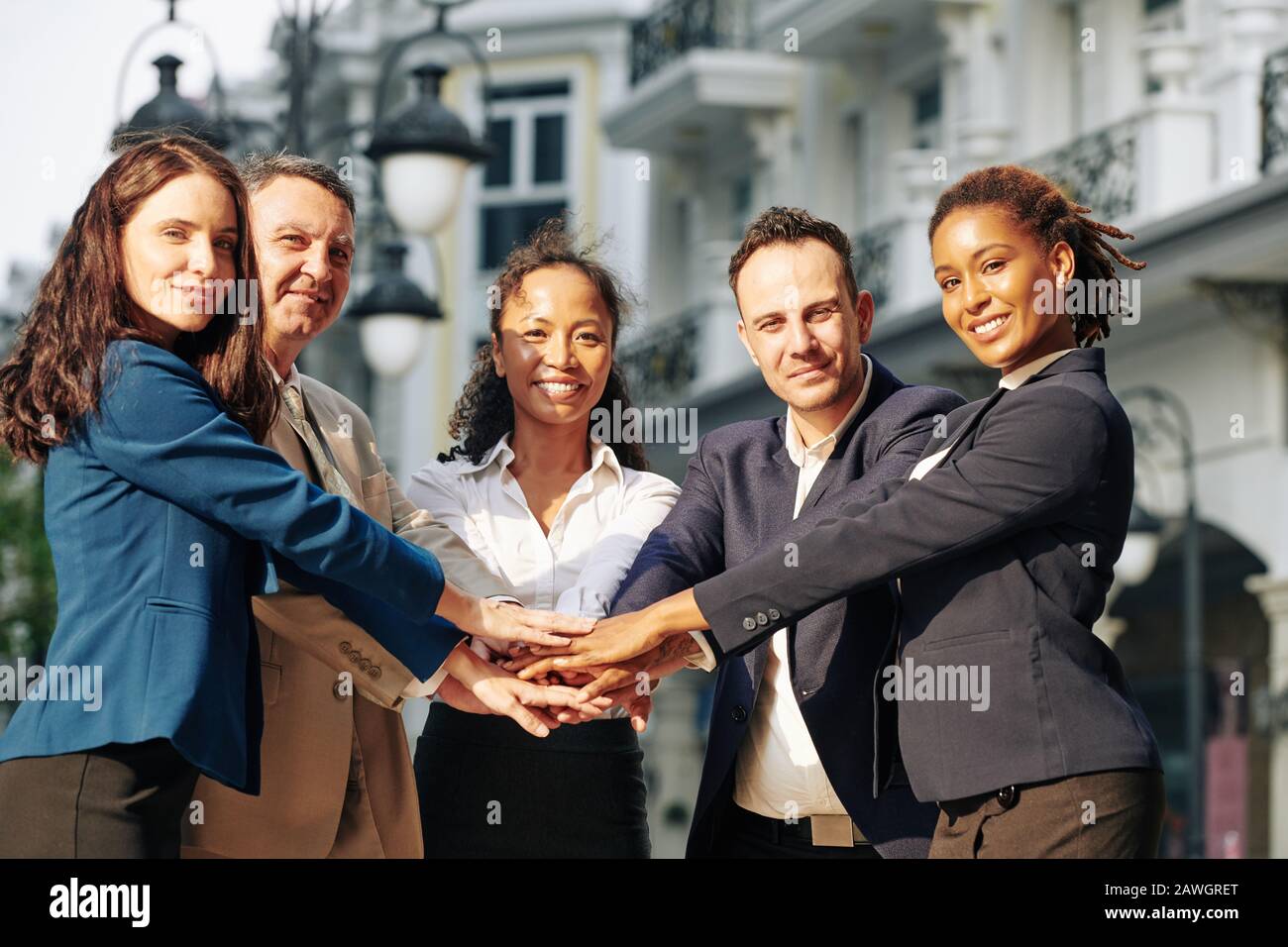 Positive multi-ethnic business team stacking hands to express support and unity Stock Photo
