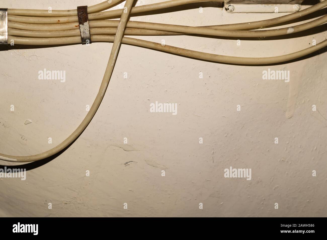 Old electrical wires or cables hanging on the wall. industrial background Stock Photo