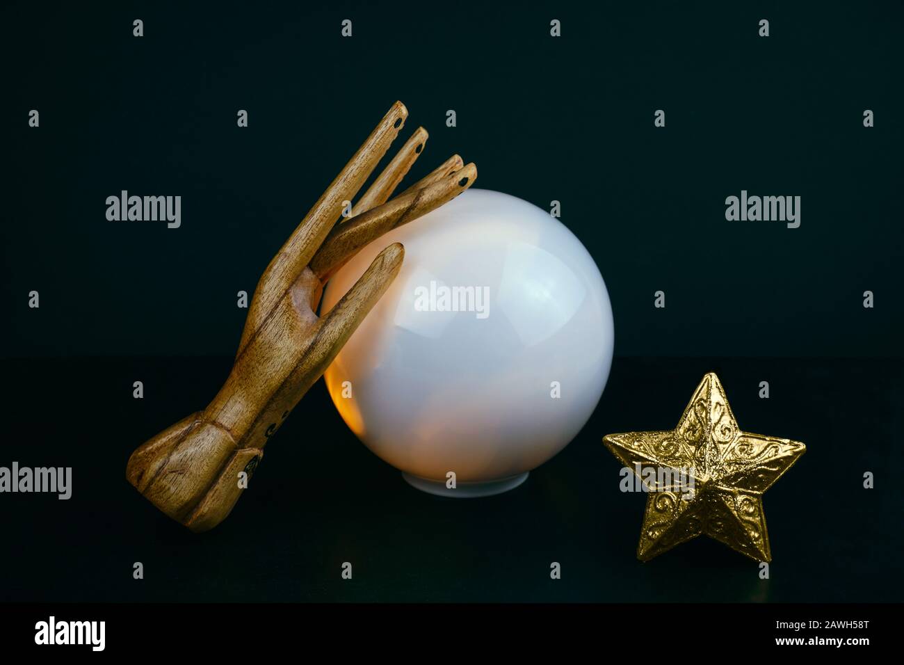 creative esoteric still life with a ball of predictions and two wooden female hands on a black background Stock Photo