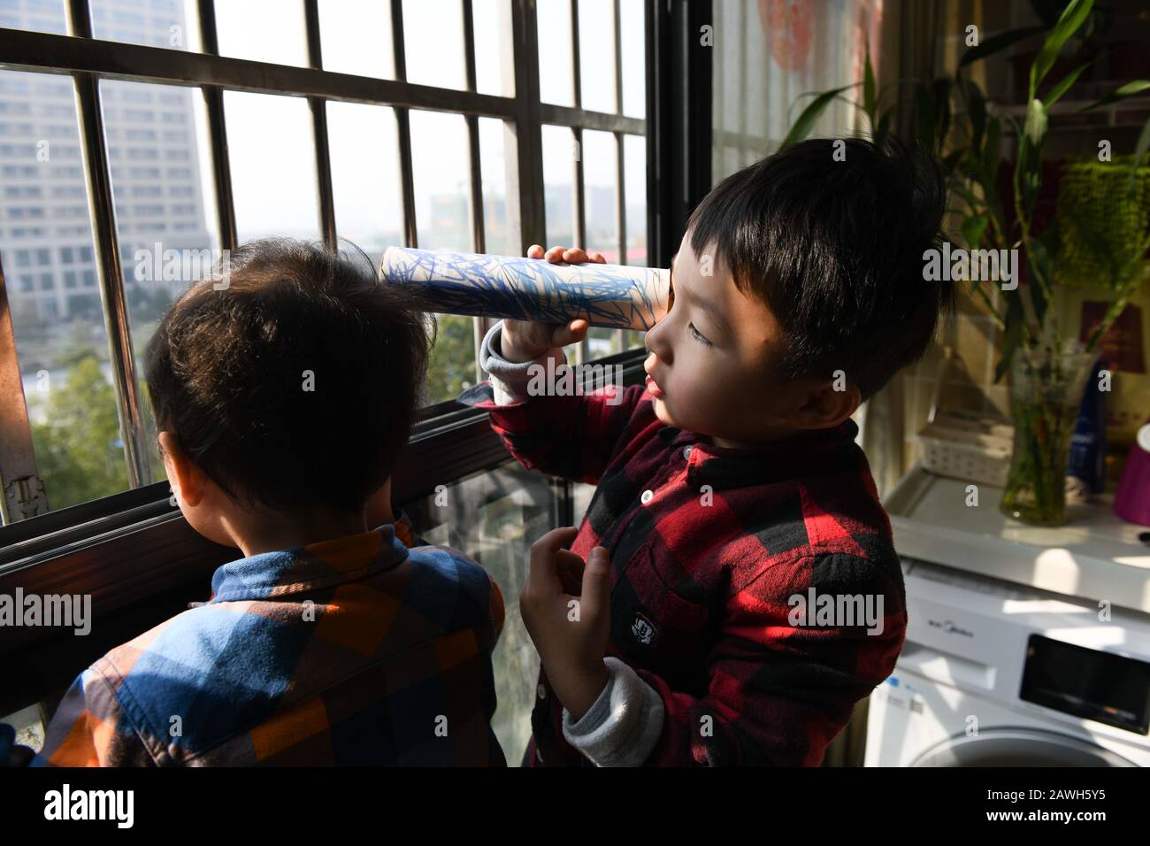 (200209) -- HEFEI, Feb. 9, 2020 (Xinhua) -- Sons of Fang Ji look toward the Second People's Hospital of Hefei on the balcony at home in Hefei, capital of east China's Anhui Province, Feb. 3, 2020. Fang Ji, 34, is a nurse who works in the ICU (intensive care unit) of the Second People's Hospital of Hefei. After the outbreak of the novel coronavirus (2019-nCov), Fang and her colleagues stay 24 hours a day in the hospital taking care of patients in shifts. The balcony of Fang's house lies in front of the hospital. In order to comfort two little sons who miss her badly at home, Fang told them that Stock Photo
