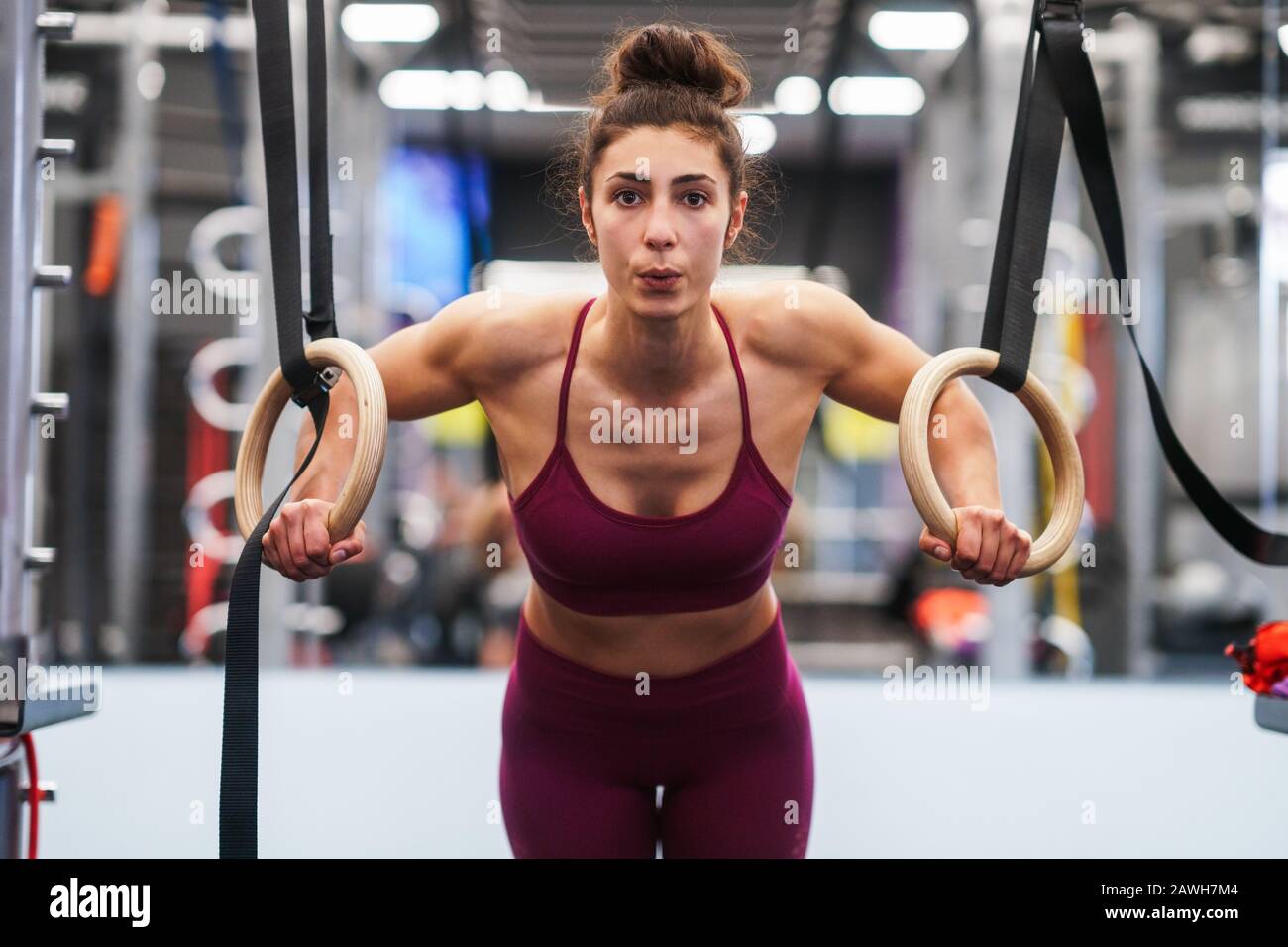 Athletic woman doing some pull up exercises in the gymnastic rings