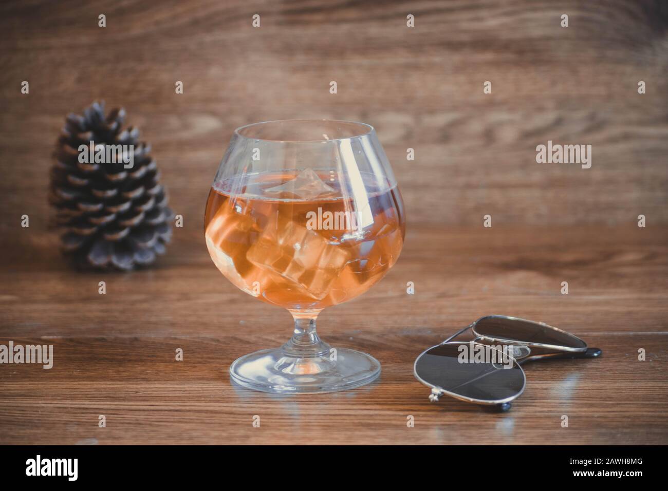 Business composition with glass with delicious whiskey next to aviator lenses. on oak boards Stock Photo