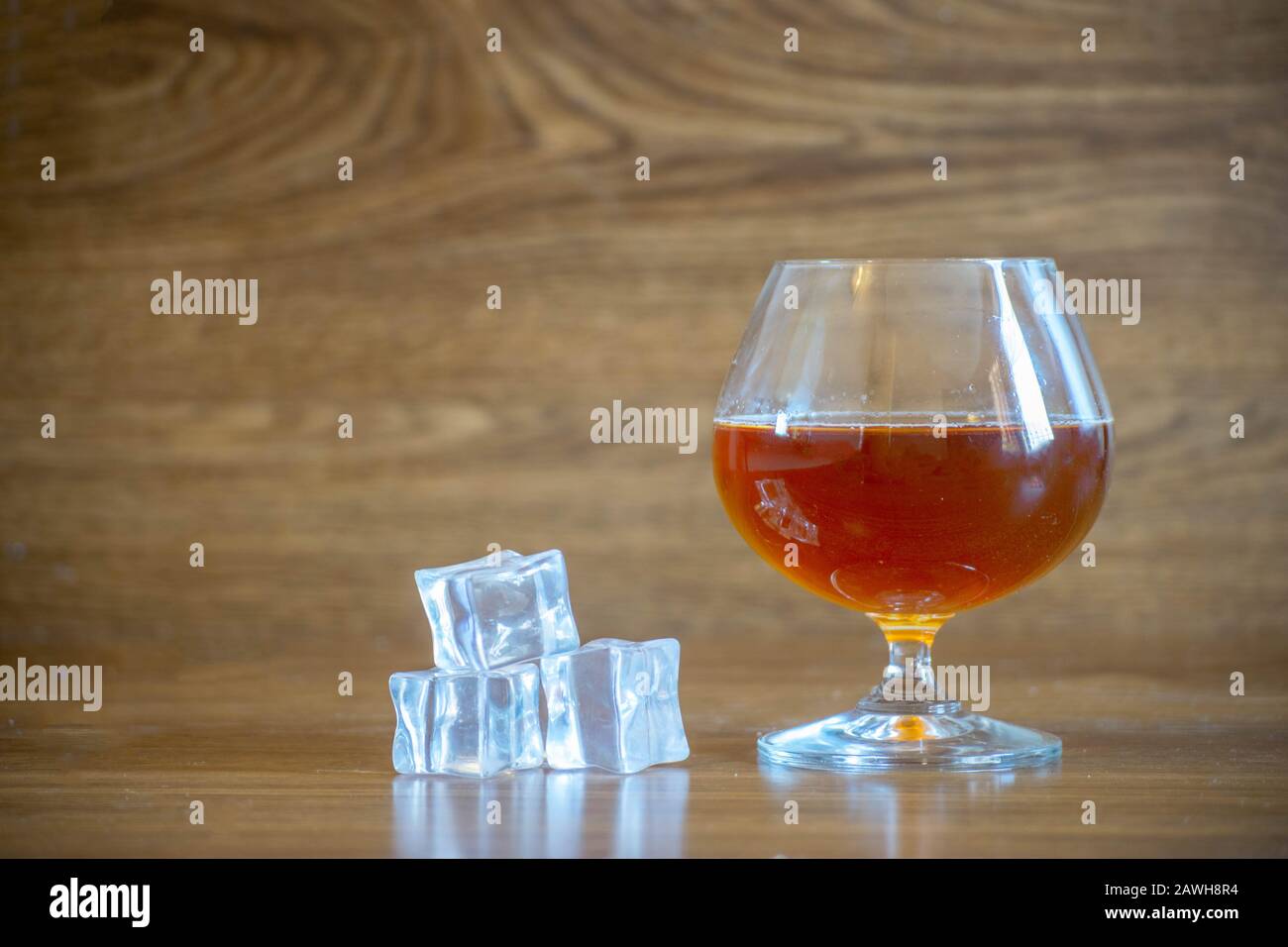 Composition with glass with delicious whiskey next to ice cubes. on oak boards Stock Photo