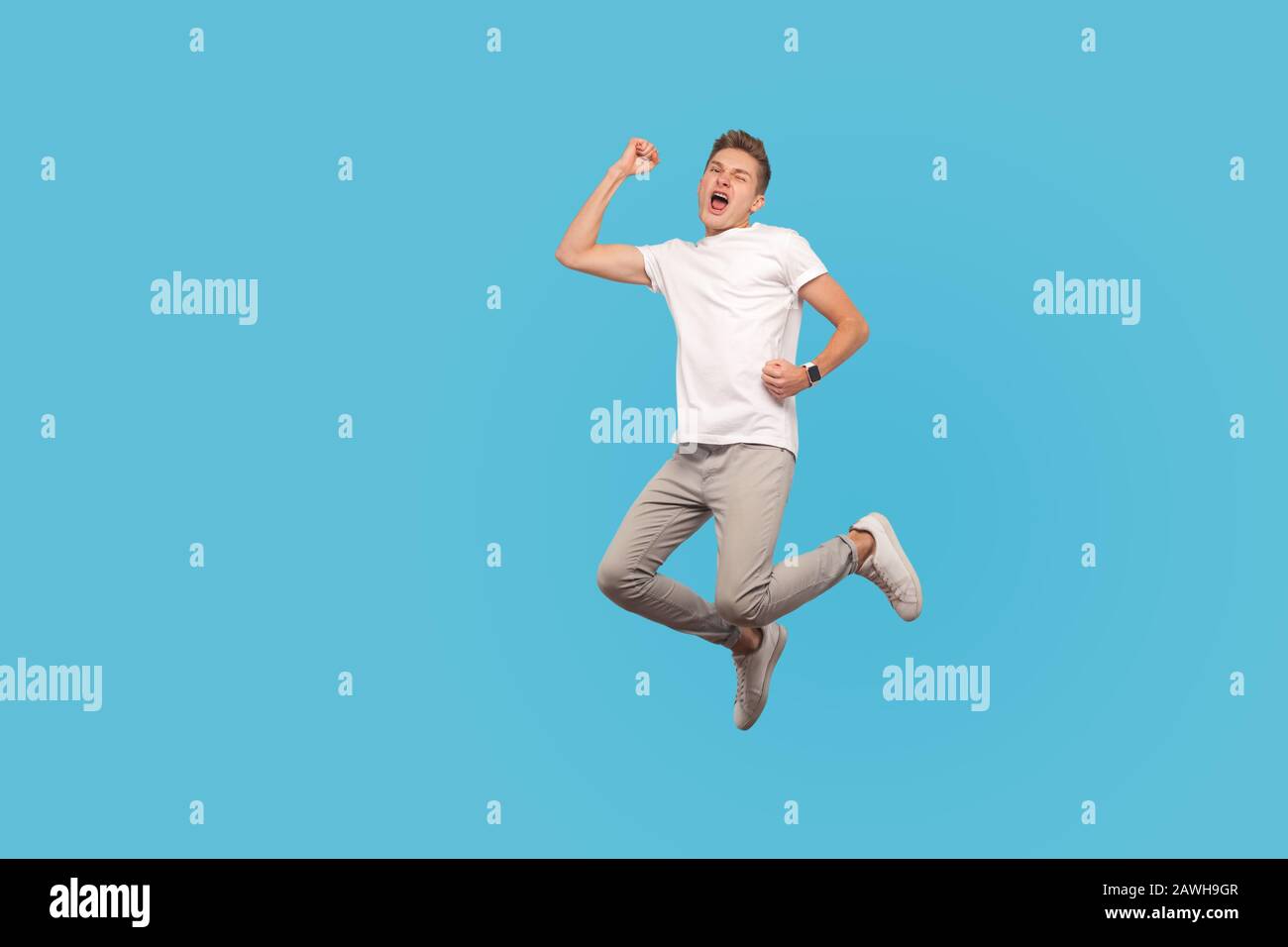 Full length portrait of successful overjoyed man in white t-shirt and casual pants jumping with happiness, screaming yes, I did it, rejoicing winning. Stock Photo