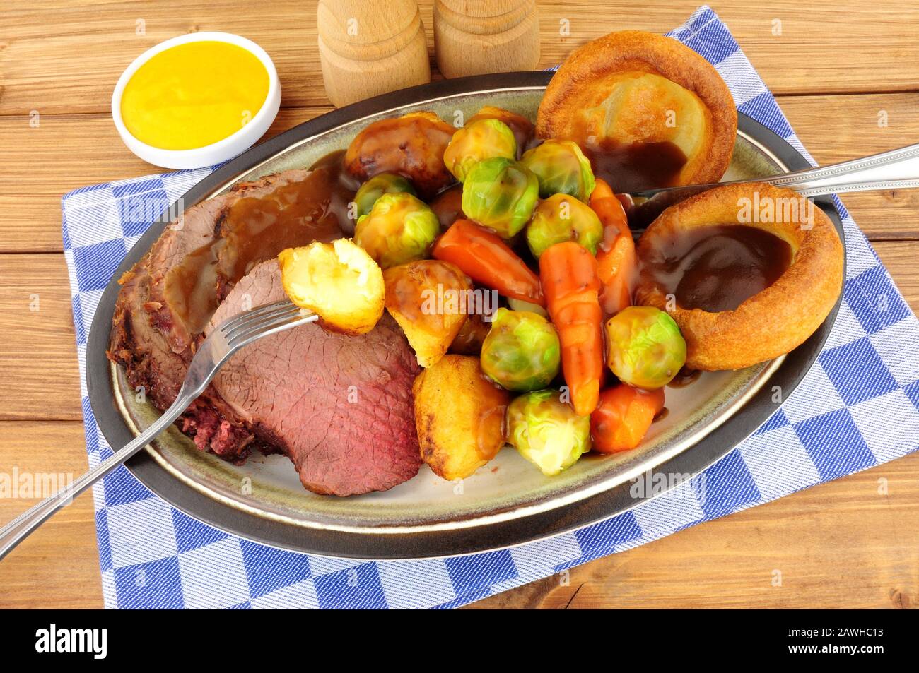 Traditional English roast beef meal with roasted potatoes, vegetables and Yorkshire puddings