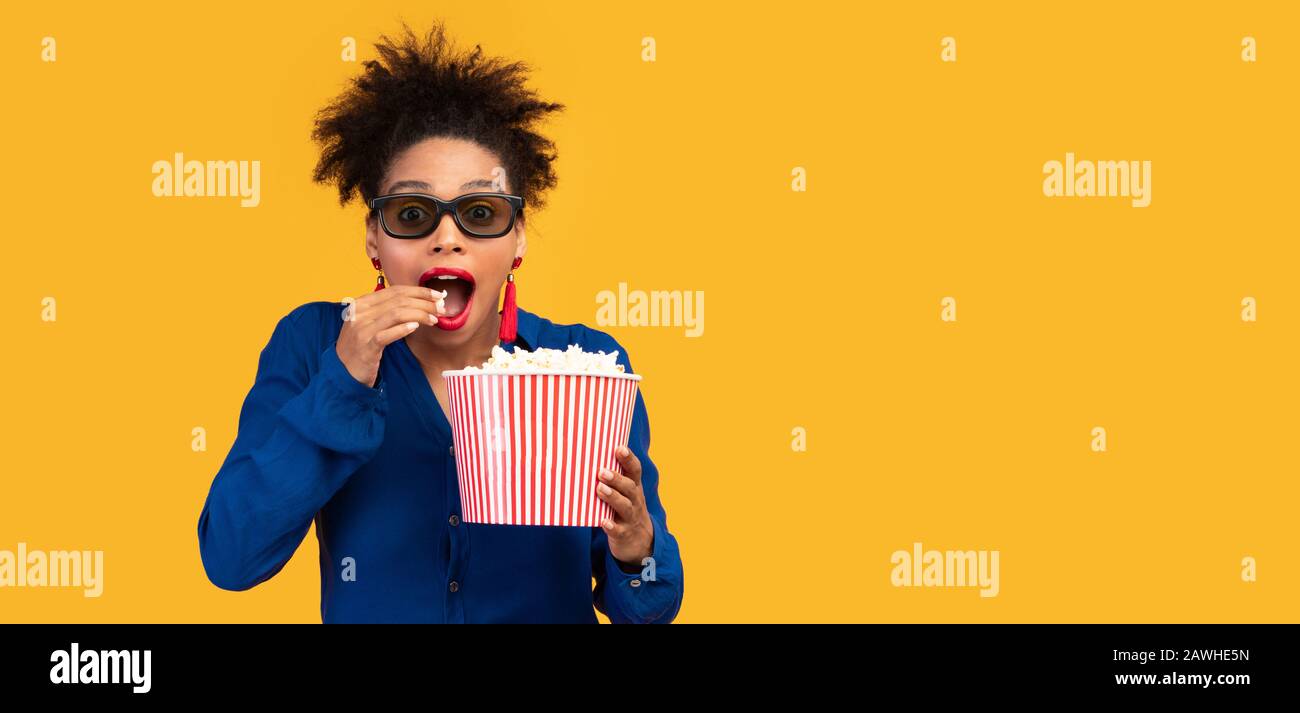 Millennial afro woman with popcorn looking at camera Stock Photo