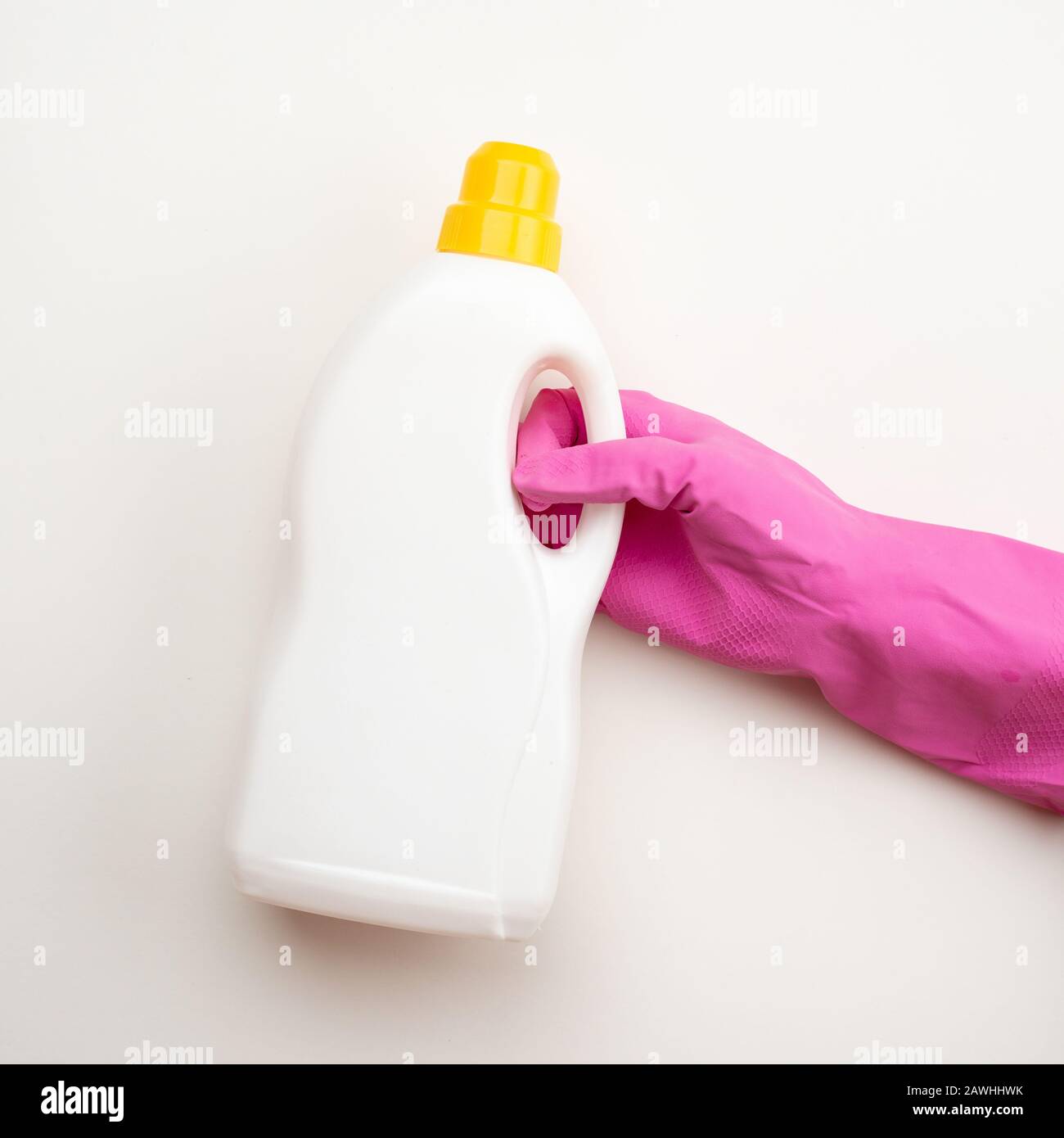 Closeup hand wearing in latex glove holding a Detergent bottle with yellow cap on white