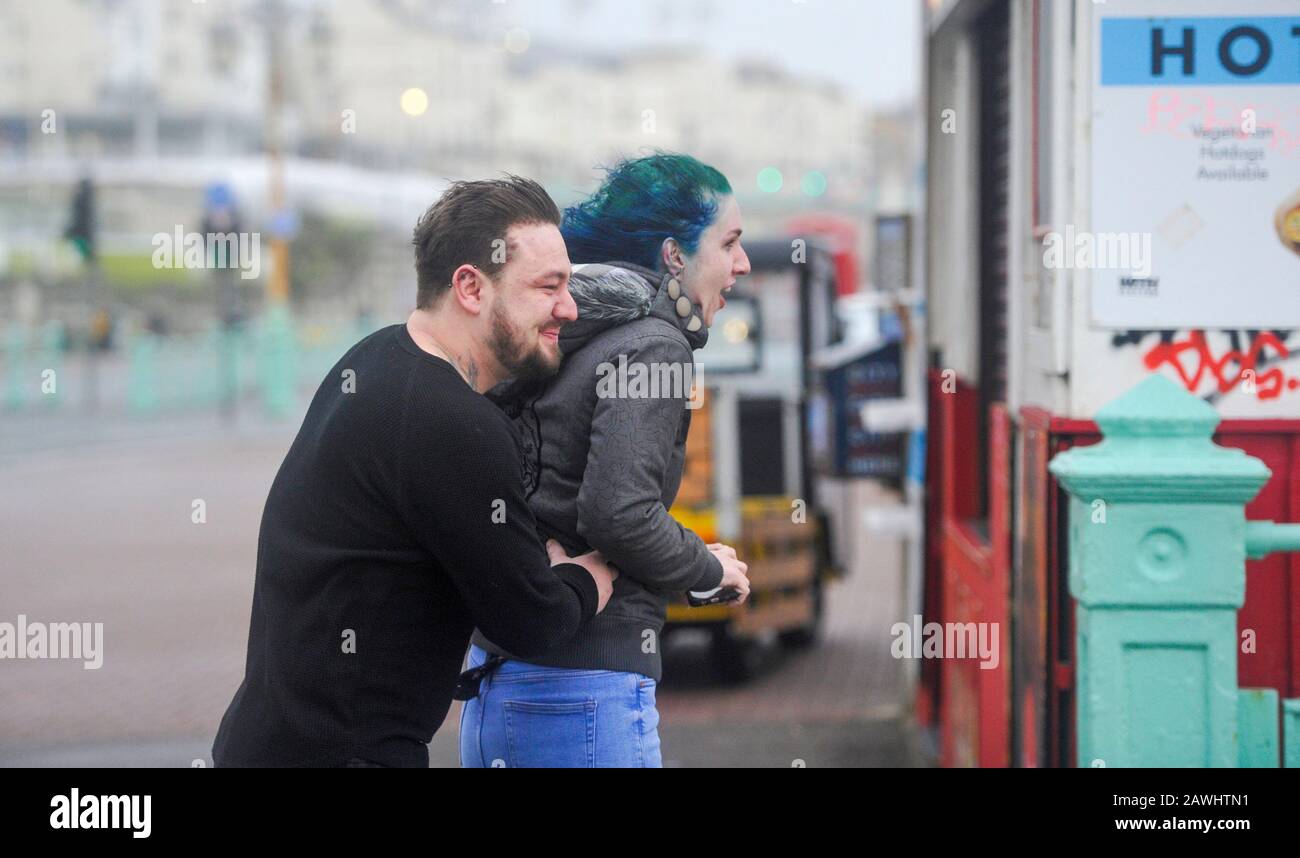Brighton UK 9th February 2020 - A couple hang on to each other on Brighton seafront in strong winds as Storm Ciara hits Britain with amber warnings being given throughout the country as high winds are expected to cause damage and possible danger to life: Credit Simon Dack / Alamy Live News Stock Photo