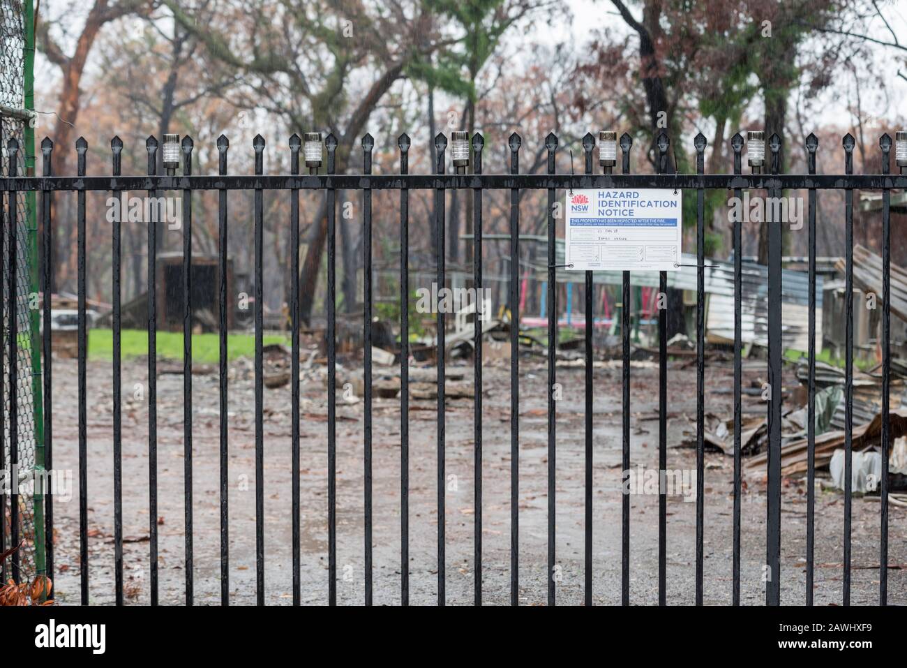 Tarmoor NSW Australia Feb 9 2020:  A New South Wales government Hazardous Materials sign is attached to the gate to a property burned to the ground in the December 2019 bush fires. Unfortunately too late for this property, most eastern parts of New South Wales have received much needed rains that have filled farm dams, greened gardens and started the recovery of fire ravaged bushland. This property however remains a sodden muddy pile of rubble. Photo Credit Stephen Dwyer Alamy Stock Photo