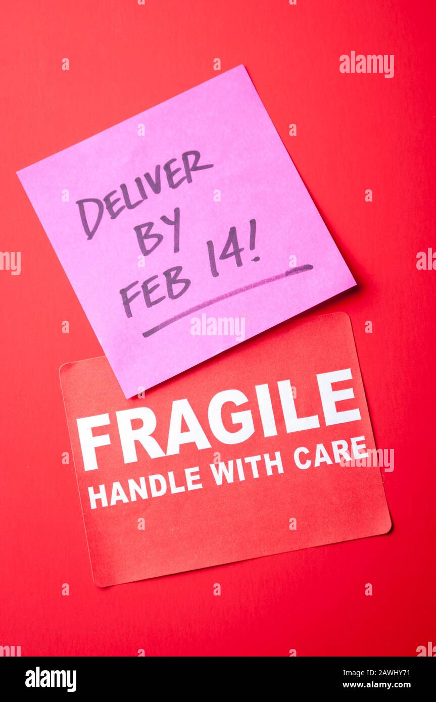 Bright red package with Fragile sticker and Deliver by Feb 14! message Stock Photo