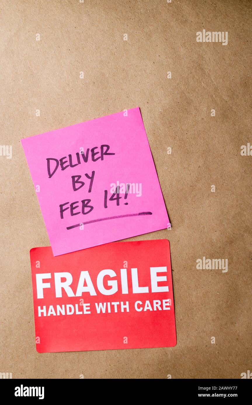 Plain brown package with Fragile sticker and Deliver by Feb 14! message Stock Photo