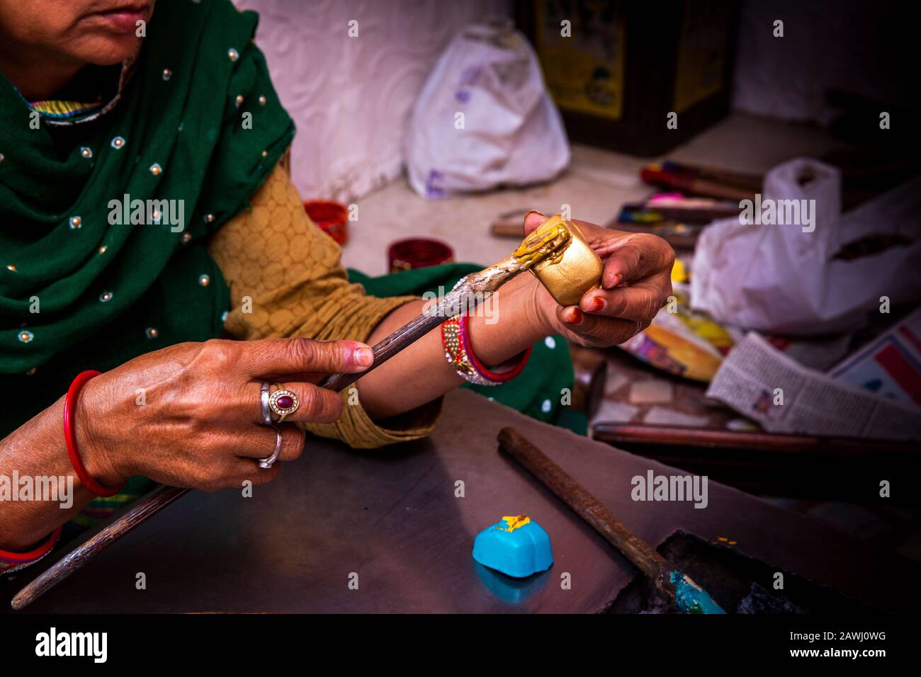 India, Rajasthan, Shekhawati, Nawalgarh, making traditional lac bangles by hand, forming pattern, attaching melted gold colour to bangle base Stock Photo