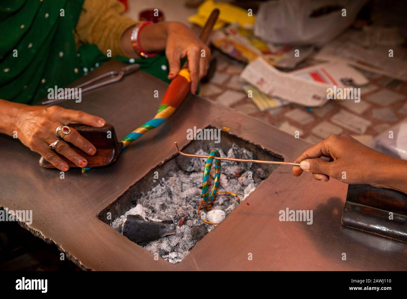 India, Rajasthan, Shekhawati, Nawalgarh, making traditional lac bangles by hand, twisting to form spiral pattern, gold and blue colour bangle, whilst Stock Photo