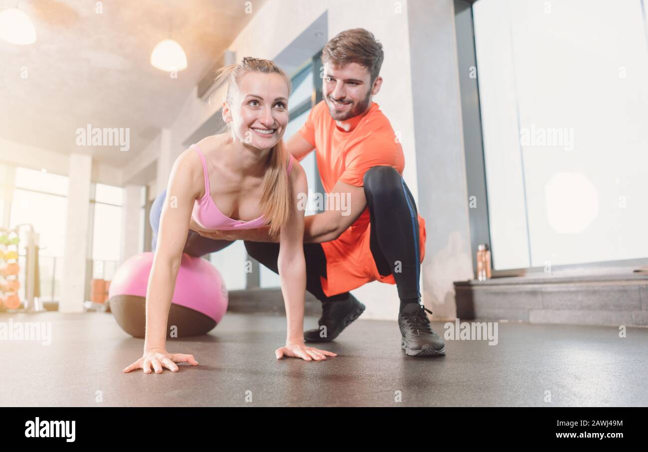 Woman with personal trainer in the gym doing pushups Stock Photo