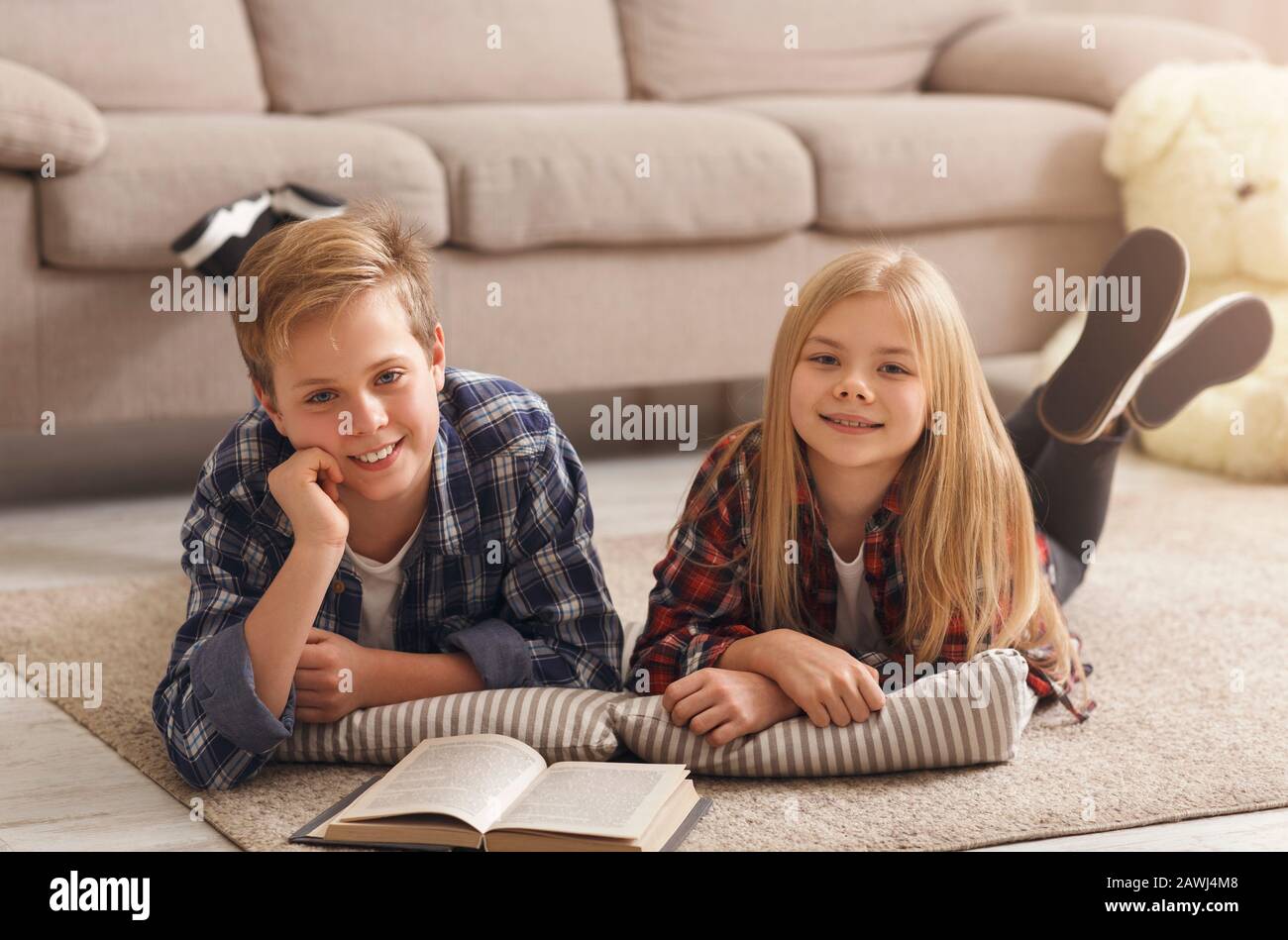 Boy And Girl Reading Book Together Lying On Floor Indoor Stock Photo